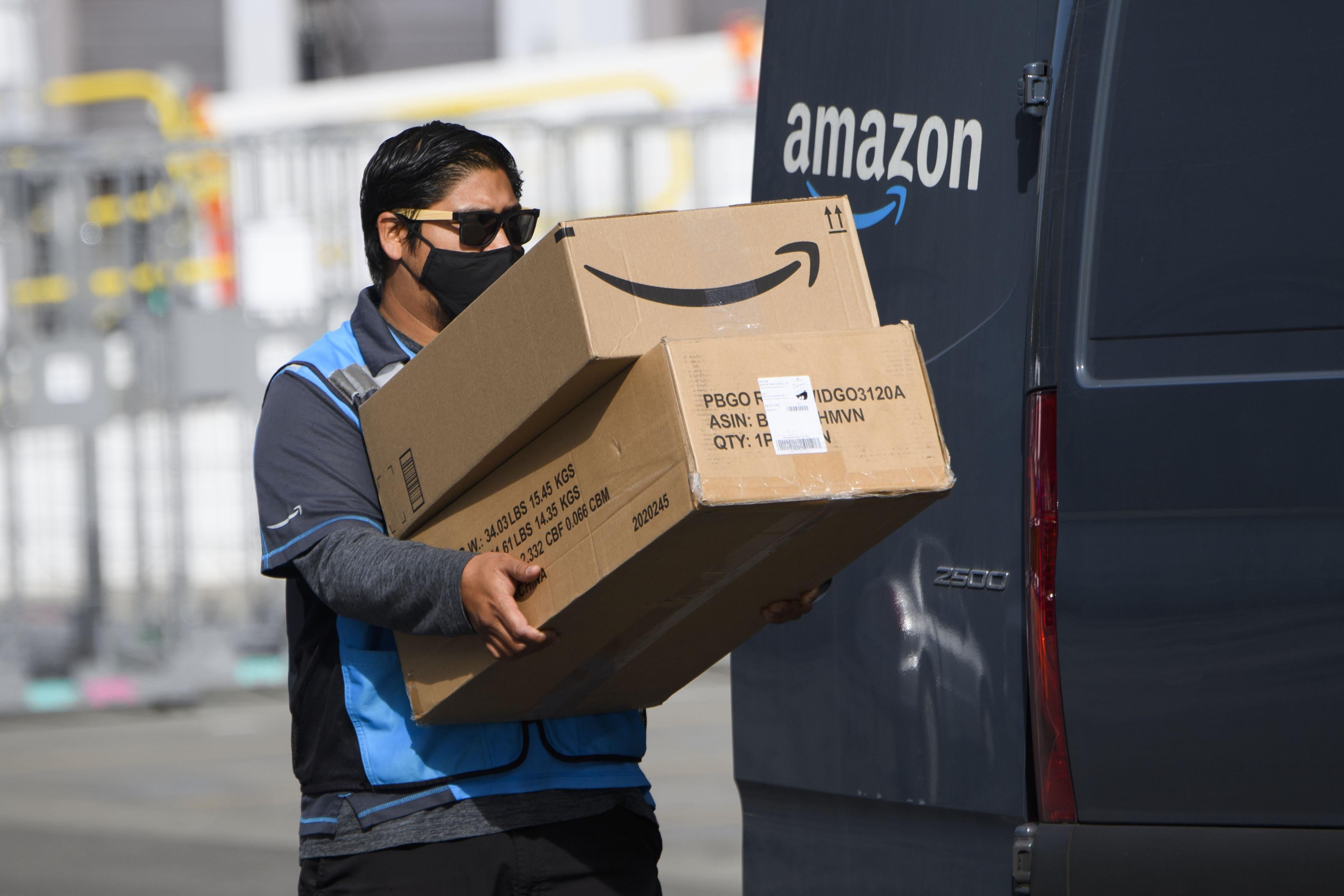 An Amazon delivery driver carries boxes into a van outside of a distribution facility on February 2, 2021 in Hawthorne, California.