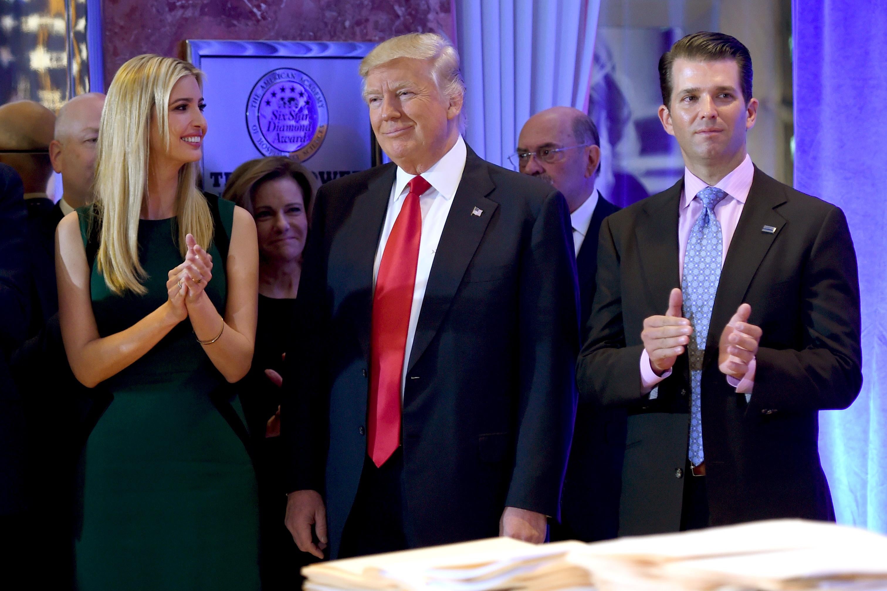 Donald Trump stands with his children Ivanka and Donald Jr., who applaud.