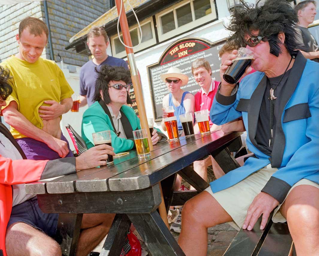 A group of friends in fancy dress drink outside The Sloop Inn pub in St Ives.
