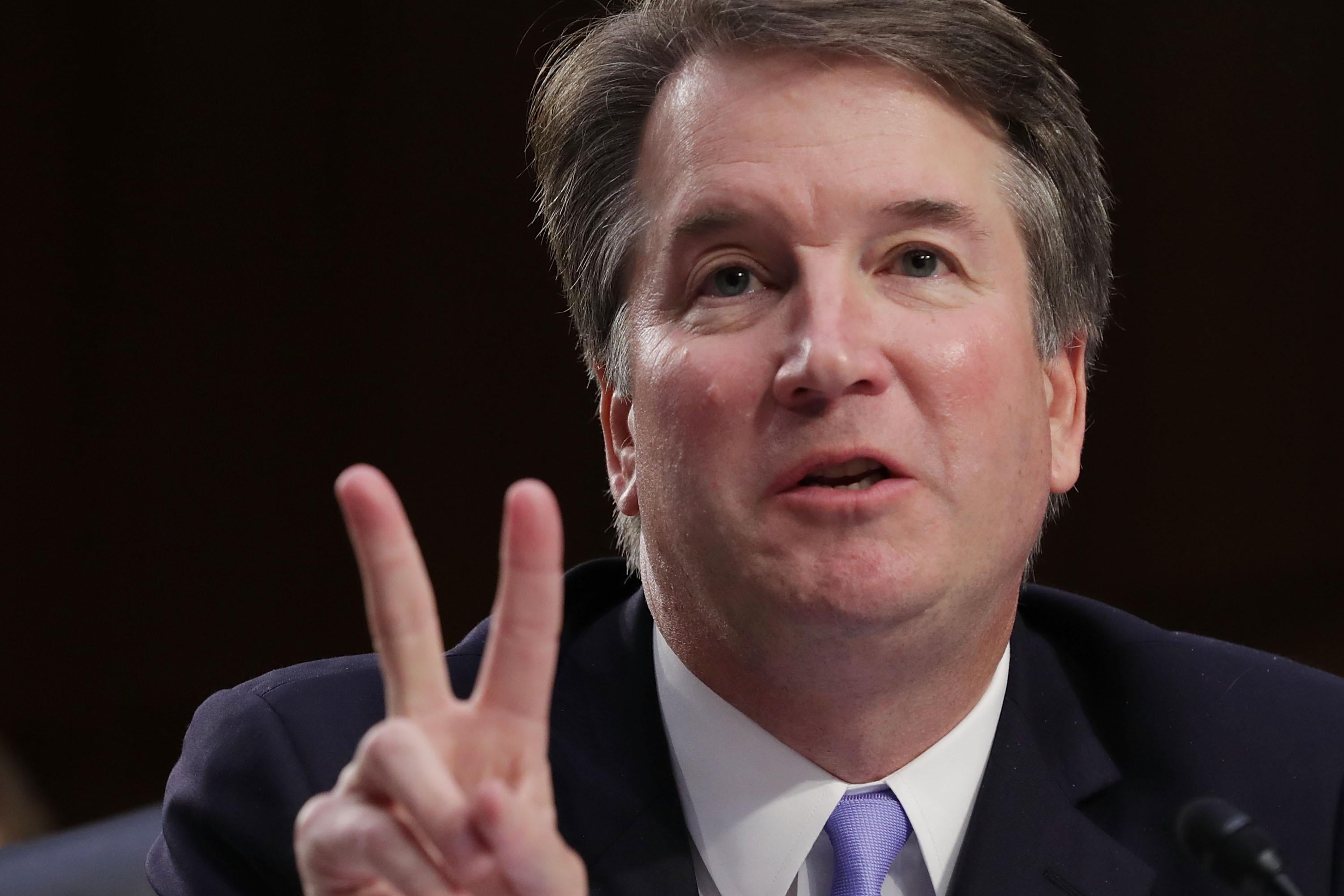 Brett Kavanaugh, making what looks like a peace sign but is probably just meant to indicate the number two.