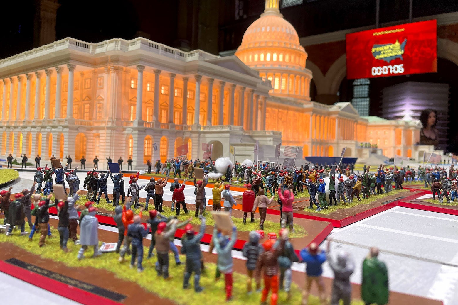 A picture of all the little figurines lined up on the game board under a dollhouse White House.