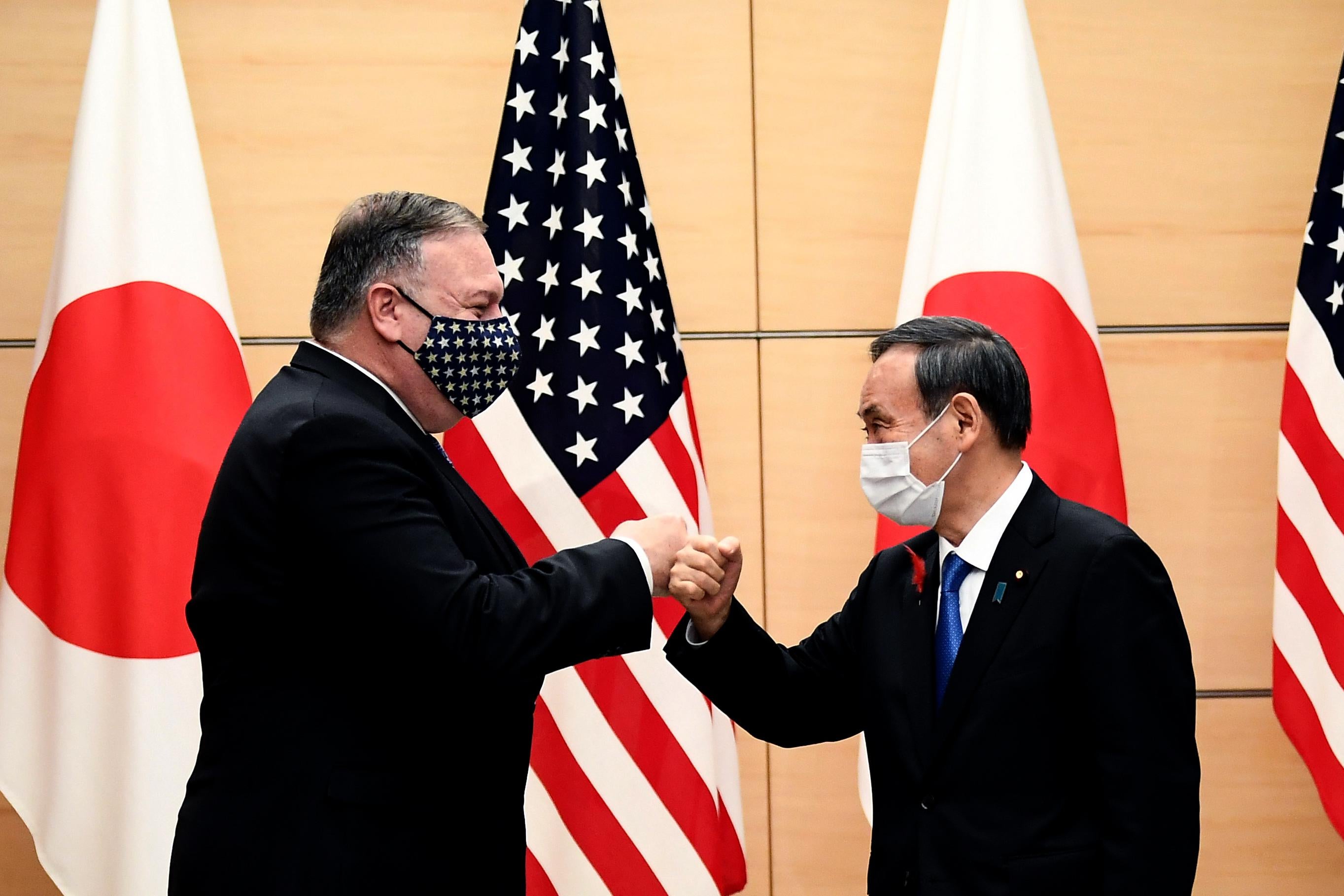 Japan's Prime Minister Yoshihide Suga and then-Secretary of State Mike Pompeo (L) bump fists as they meet at the prime minister's office in Tokyo on October 6, 2020.