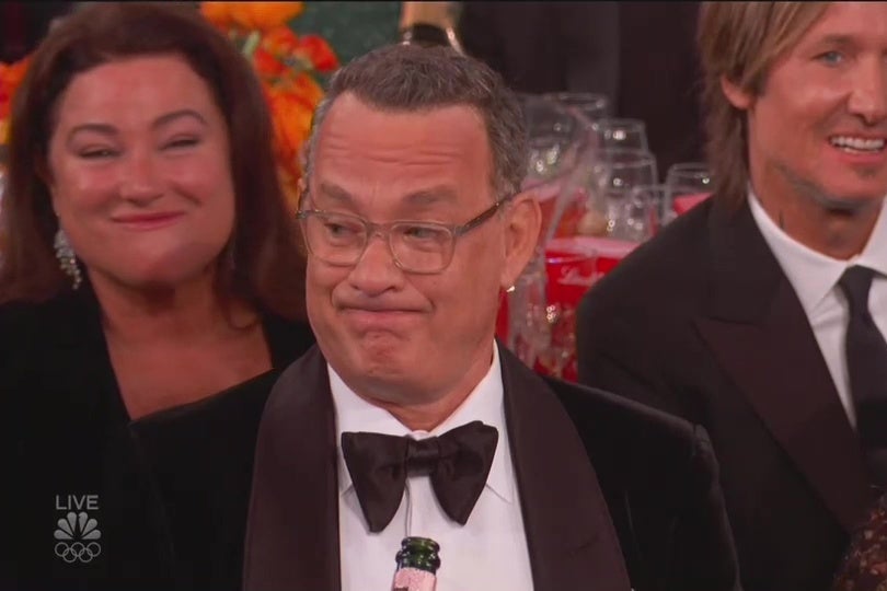 Tom Hanks, sitting at a table at the Golden Globes, making an unimpressed face.