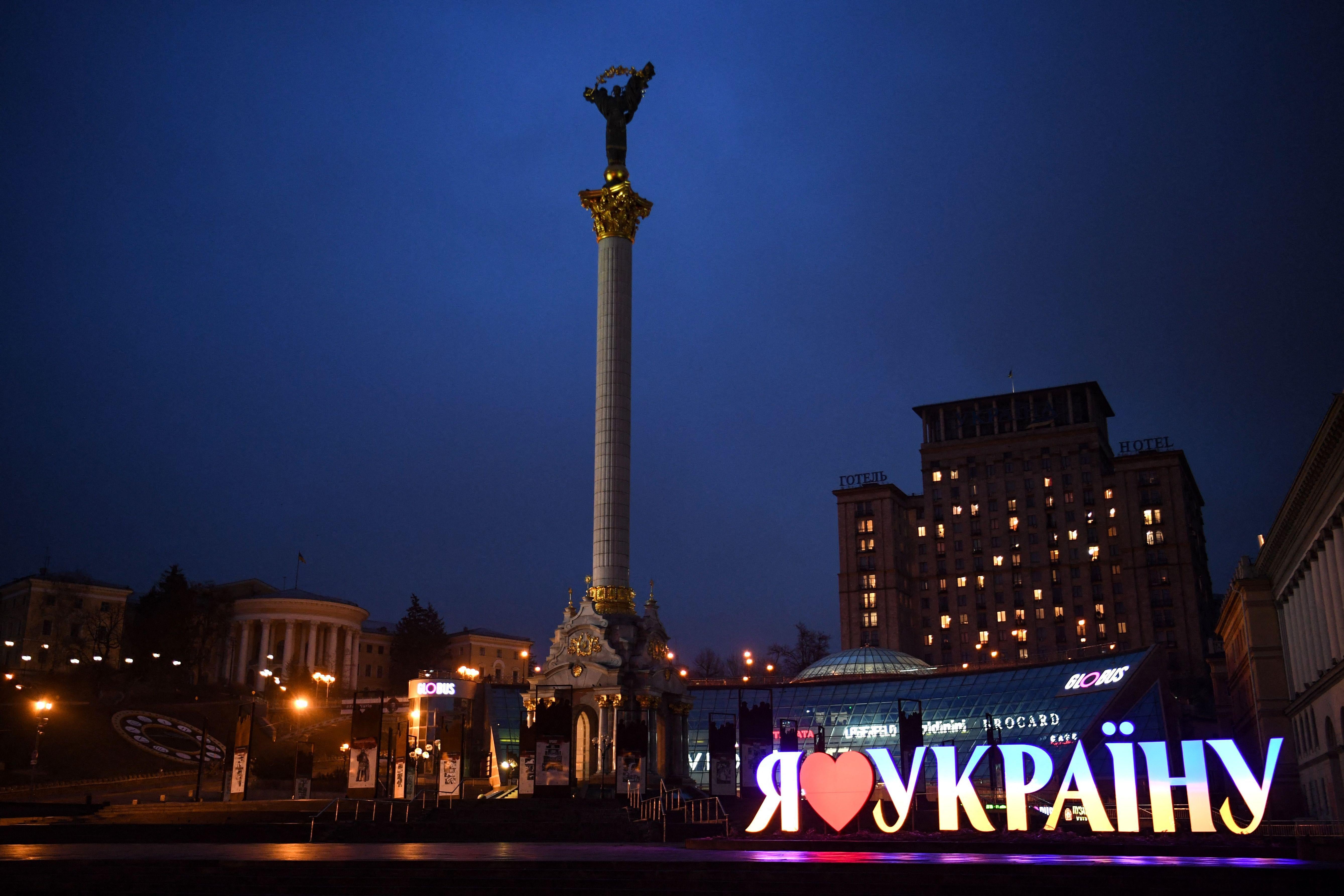 A victory column next to a lit up sign at night
