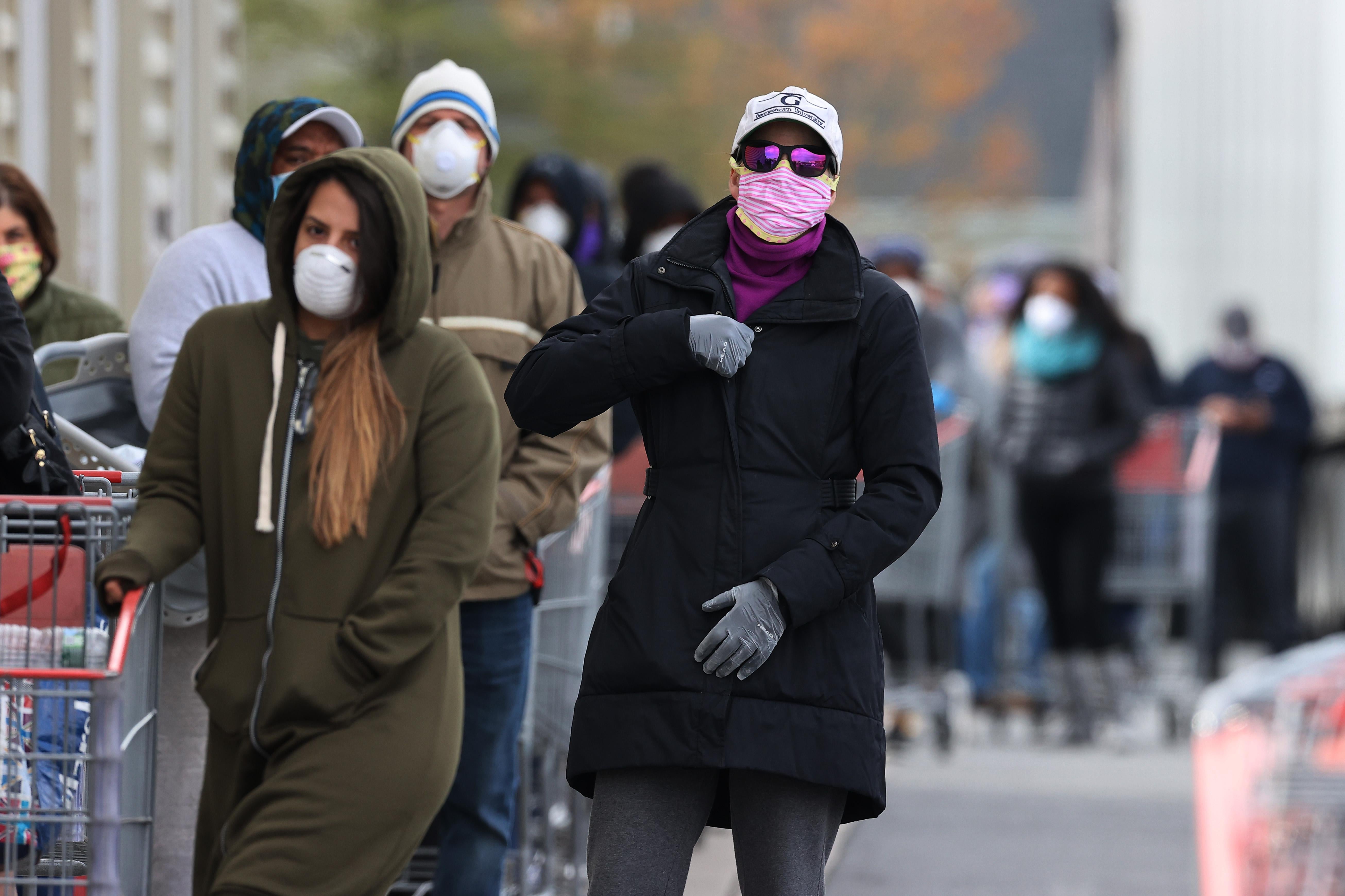 A long line of customers wearing masks and winter coats and pushing shopping carts