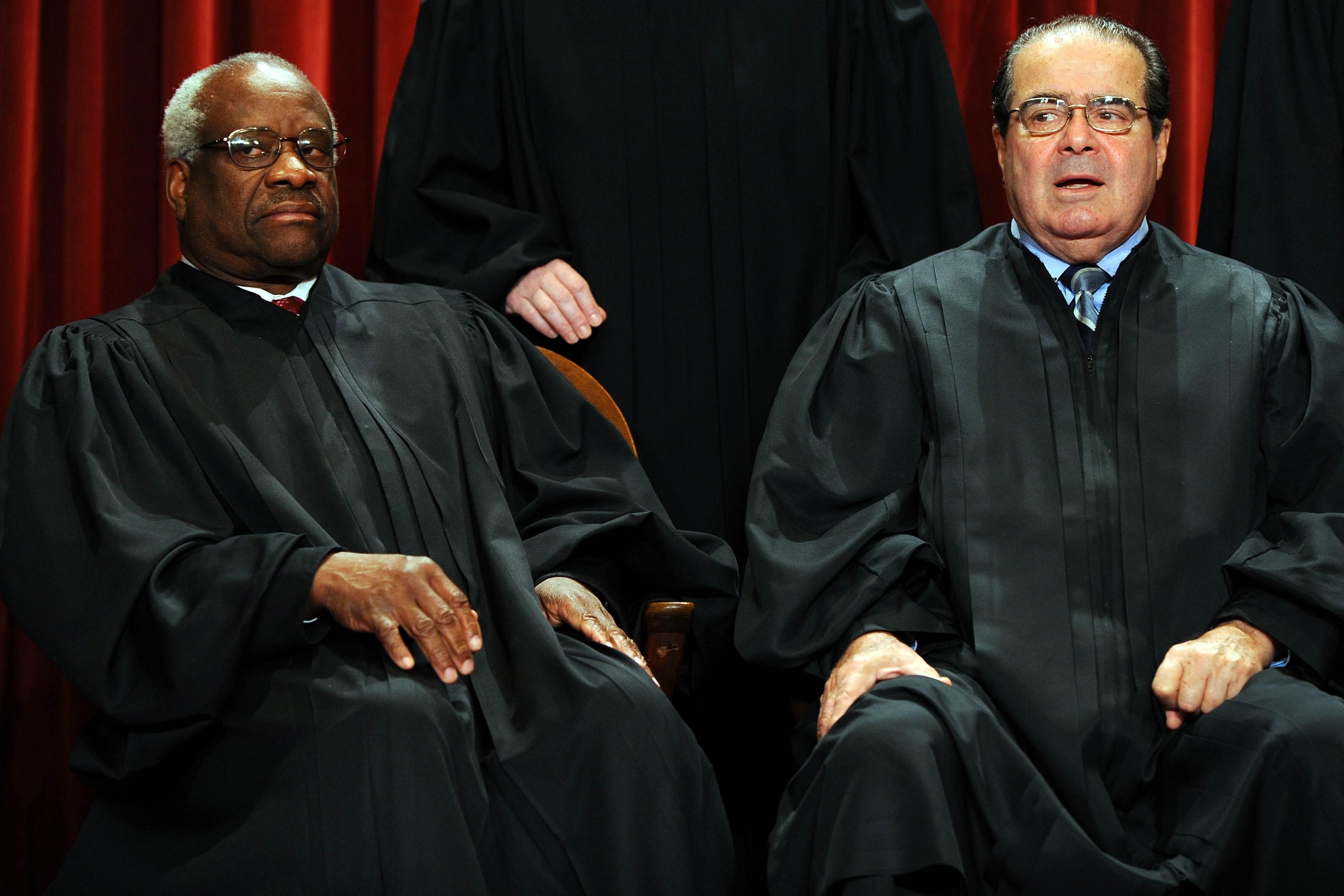 The justices seated in their robes, Thomas frowning and Scalia with his mouth agape.