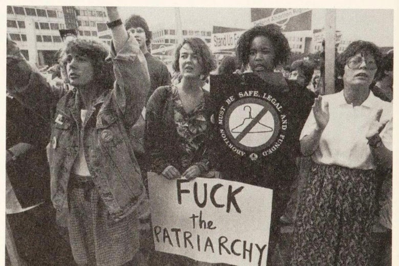 A group of women stand together holding a sign that says "Fuck the patriarchy."