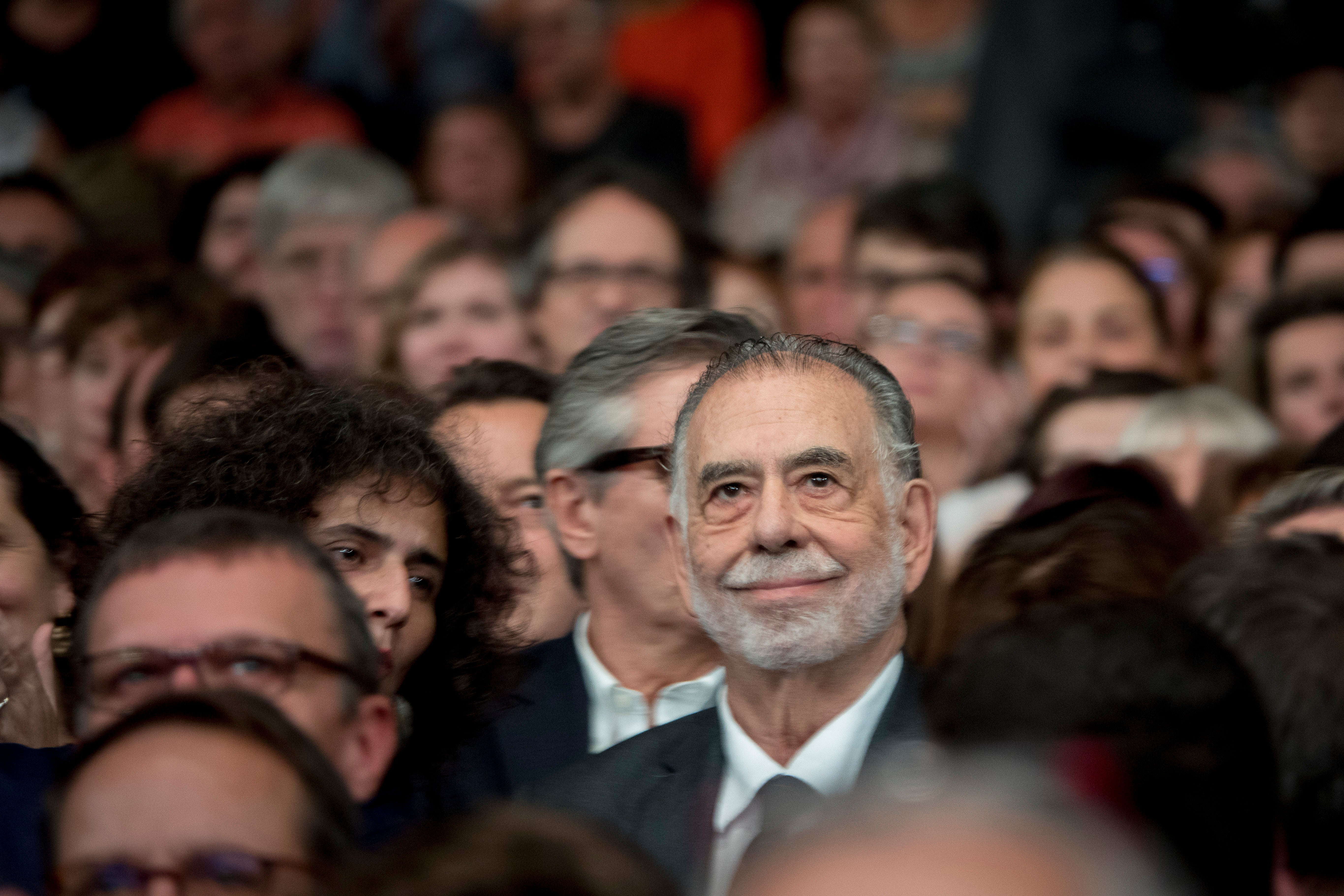 Francis Ford Coppola smiling serenely in a crowd in Lyon, France.