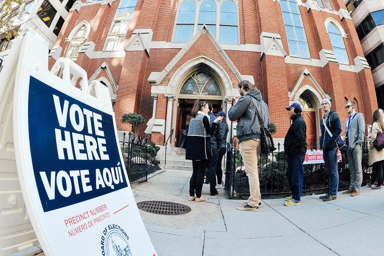 A "Vote Here/Vote Aqui" sign is seen outside the front of a church where people stand in line to go in.