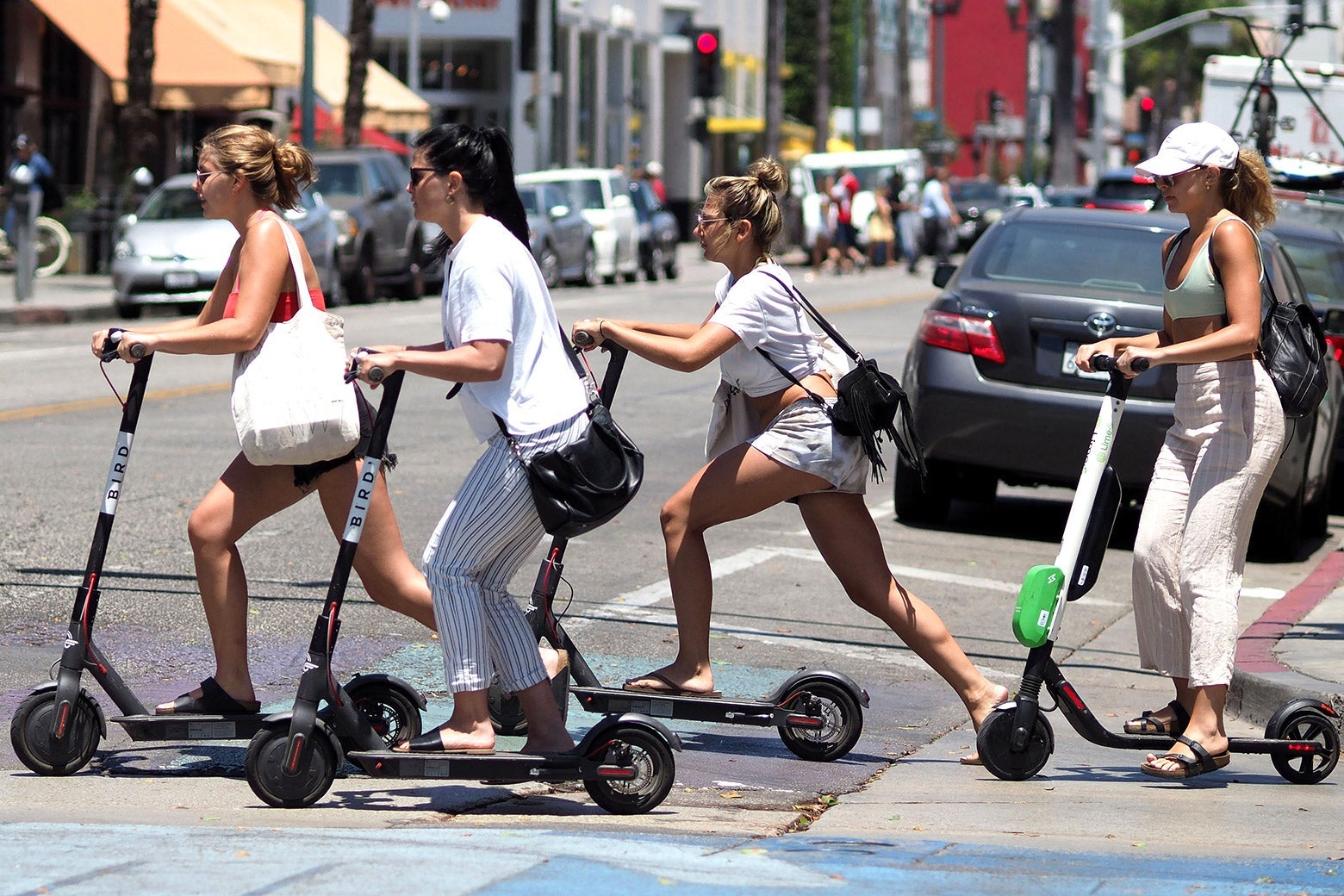 Four women ride e-scooters to cross a city street