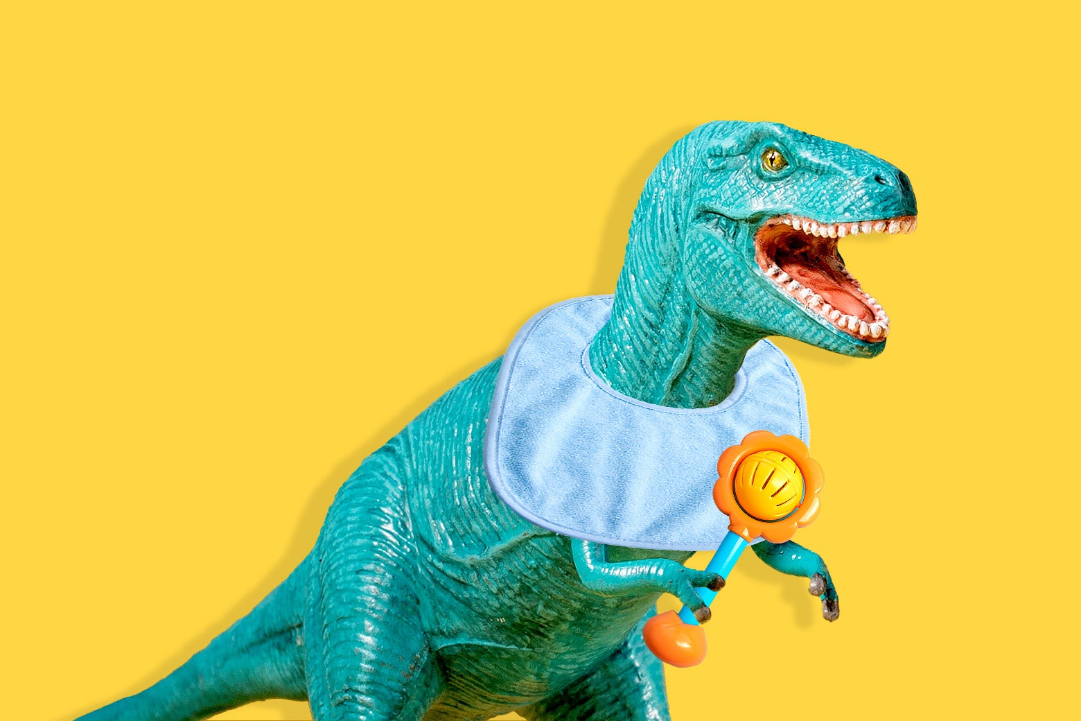 A Tyrannosaurus rex wearing a bib and holding a rattle.