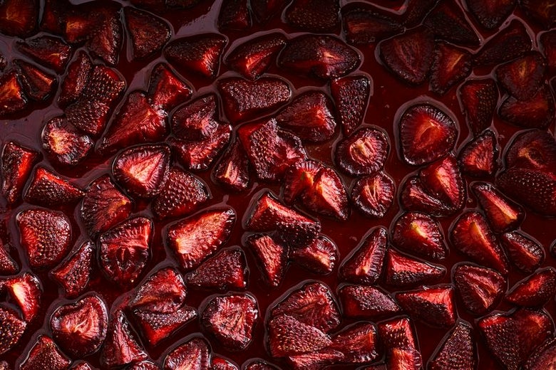 A bunch of roasted strawberry slices sit in their own, red juice.