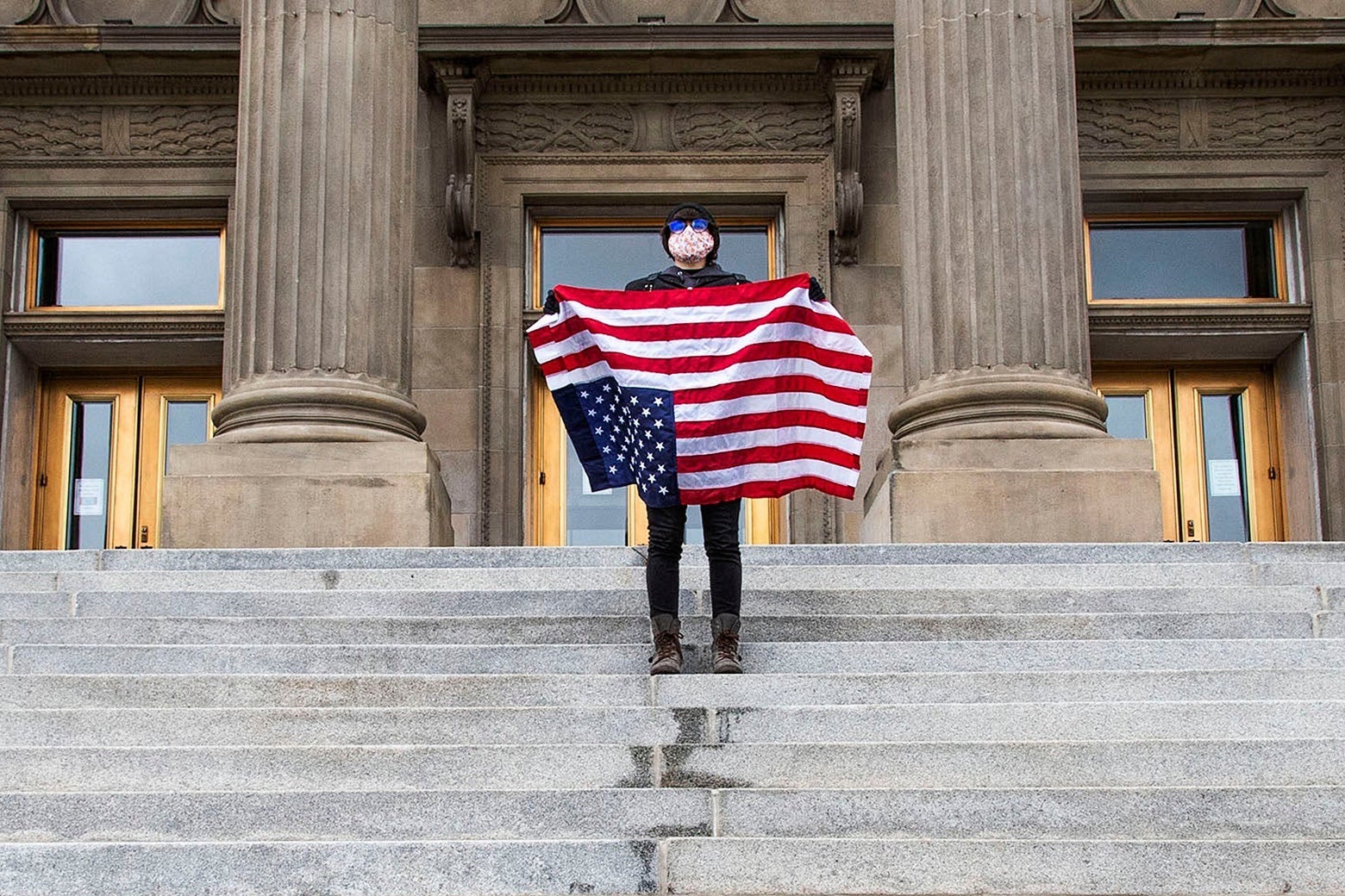 A student holding a U.S. flag upside down stands atop the steps at the Idaho Capitol Building on April 26 in Boise, Idaho.