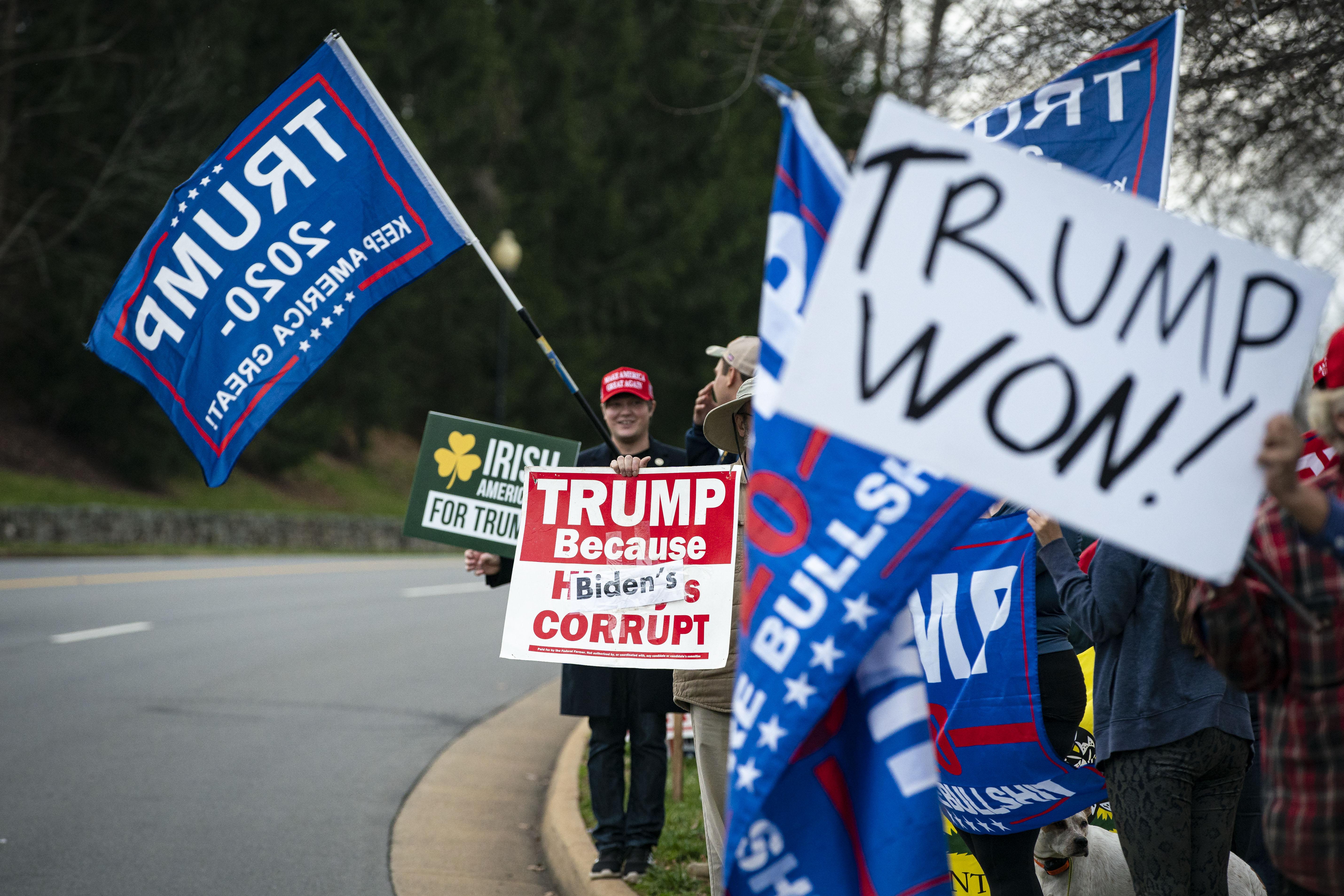 A crowd on the side of the road holding up signs that say "Trump 2020" and "Trump Won"