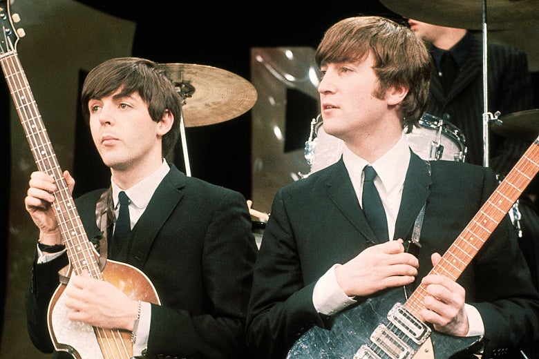 Paul McCartney and John Lennon hold their guitars while on the set of The Ed Sullivan Show on Feb. 9, 1964.