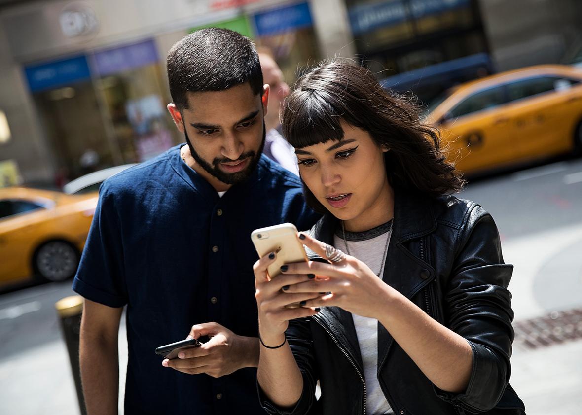 Sameer Uddin and Michelle Macias play Pokemon Go on their smartphones on Monday outside of Nintendo’s flagship store in New York City.