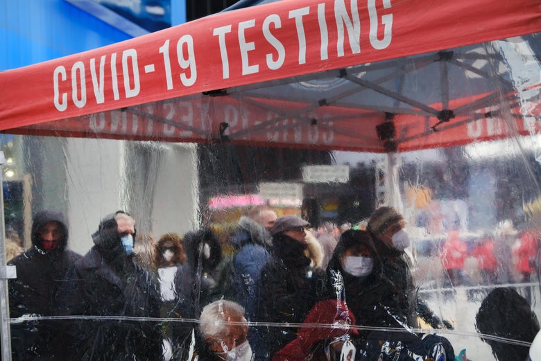 A red banner says COVID-19 TESTING. People with masks wait in line outside. 