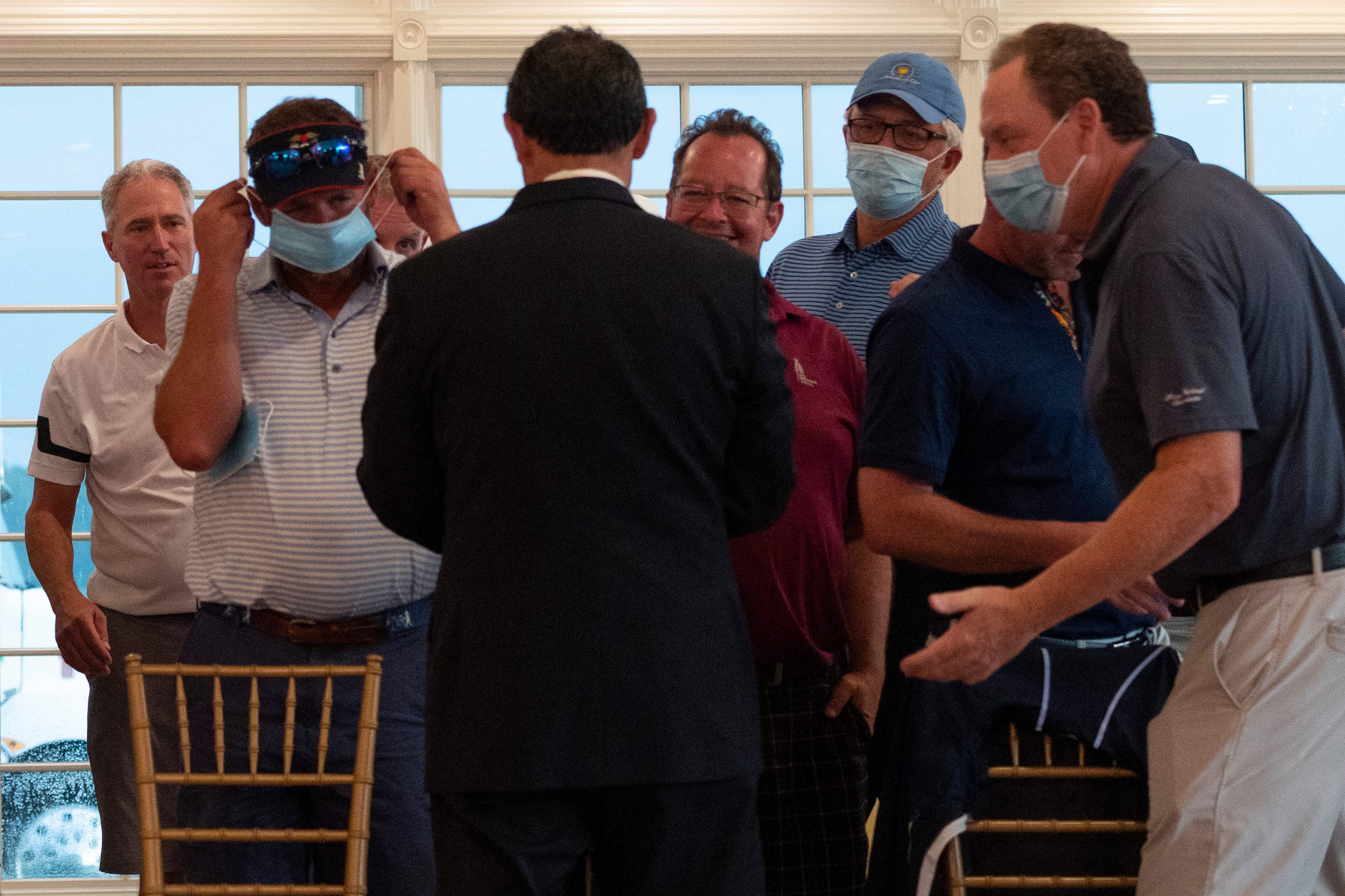 Country club members are handed facemasks to wear as they await the US president's arrival ahead of a news conference in Bedminster, New Jersey, on August 7, 2020.