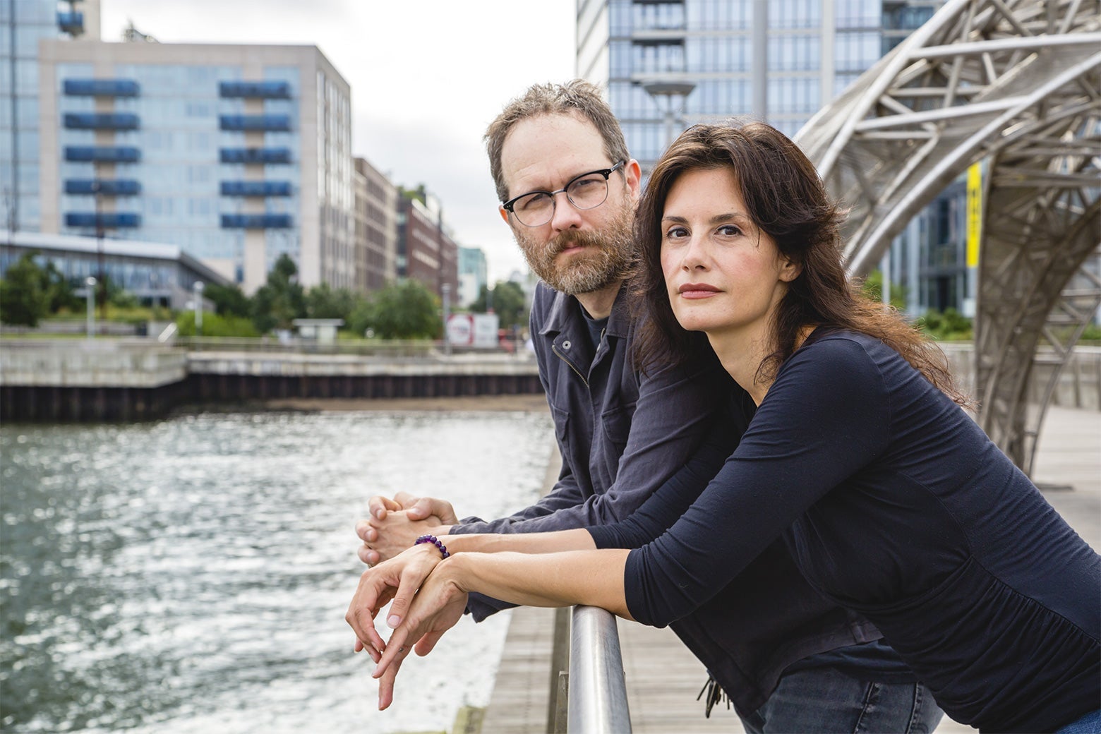 A middle-aged white man and a middle-aged white woman lean over a railing.