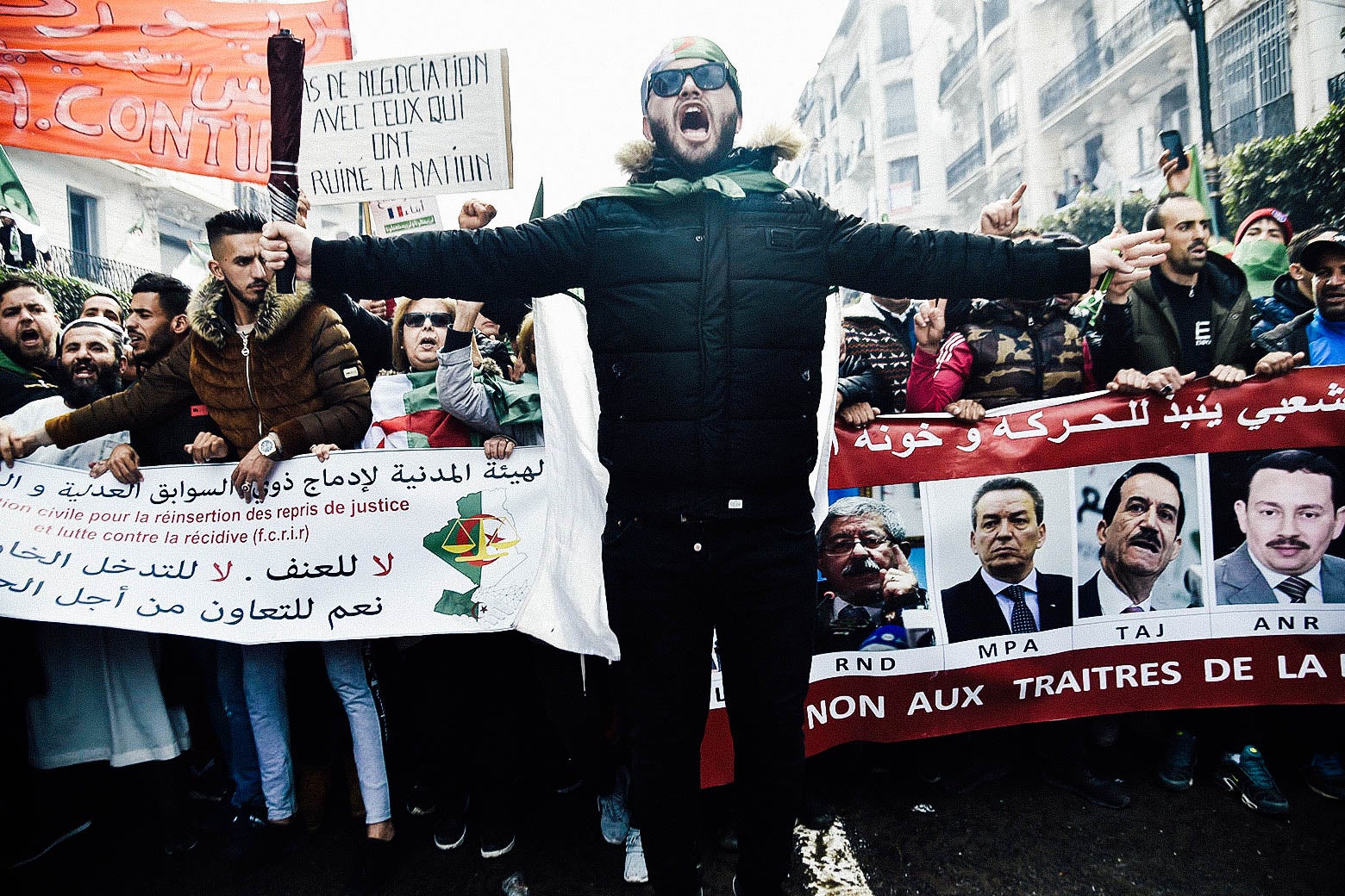 A protester jumps ahead of a marching crowd during a demonstration against ailing President Abdelaziz Bouteflika.