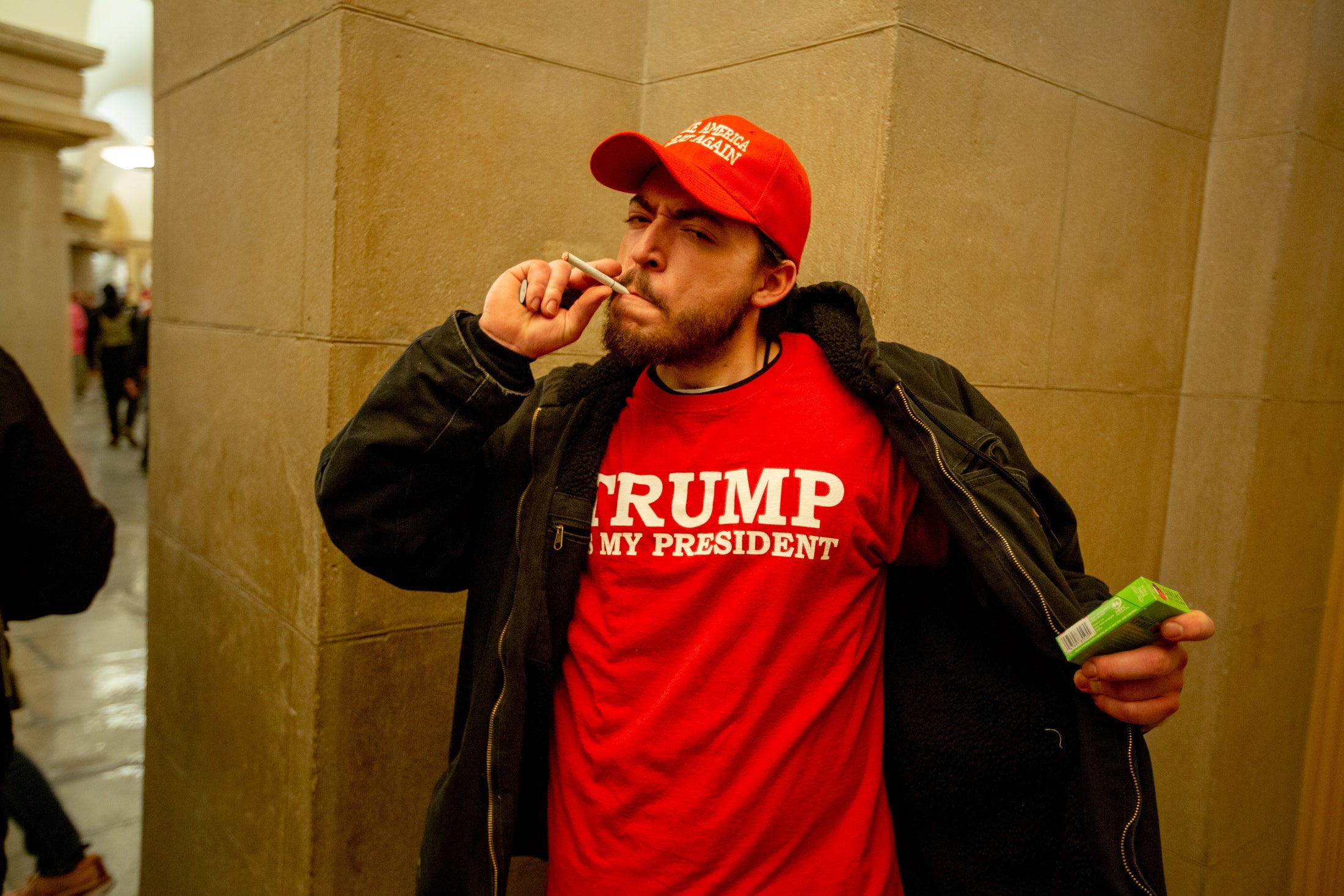 A man smoking a cigarette in a Trump Is My President T-shirt.