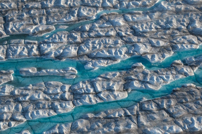 Aerial view of rivers of meltwater carving into the Greenland ice sheet near Ilulissat, Greenland.