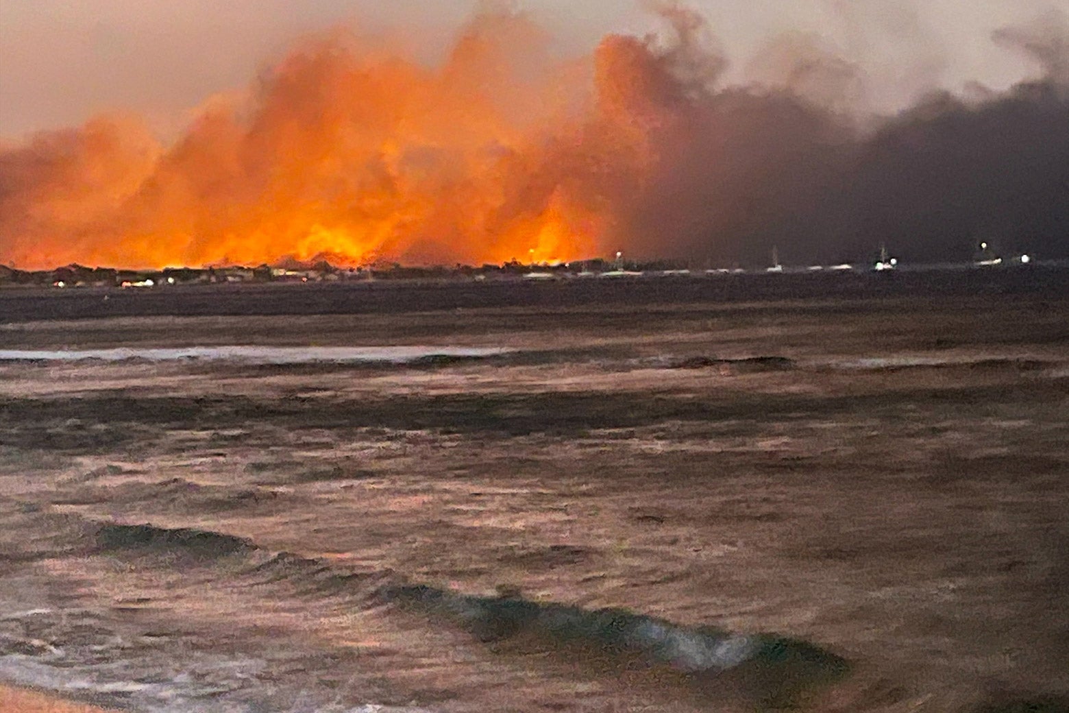 A view of a burning wildfire from a body of water.