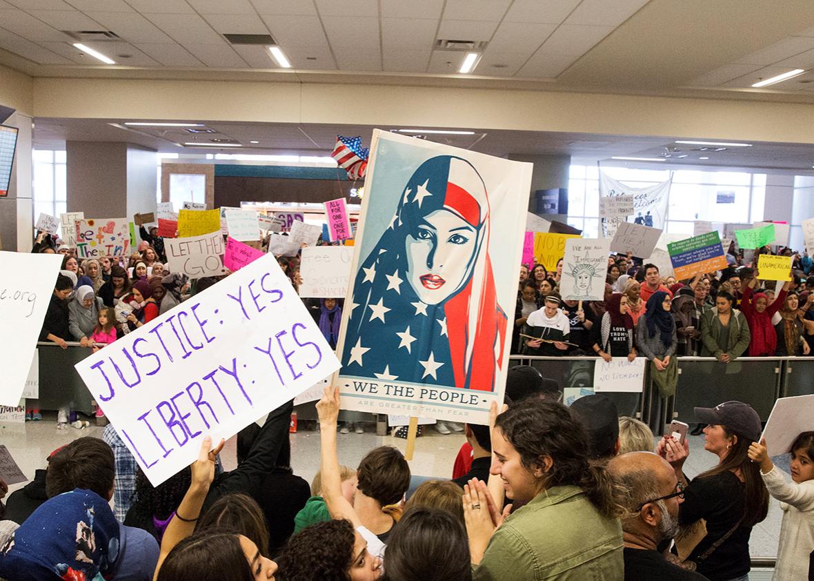 People chant and hold signs as they protest against the travel ban imposed by U.S. President Donald Trump's executive order, at Dallas/Fort Worth International Airport International Arrivals gate in Dallas, Texas, U.S. January 29, 2017. 