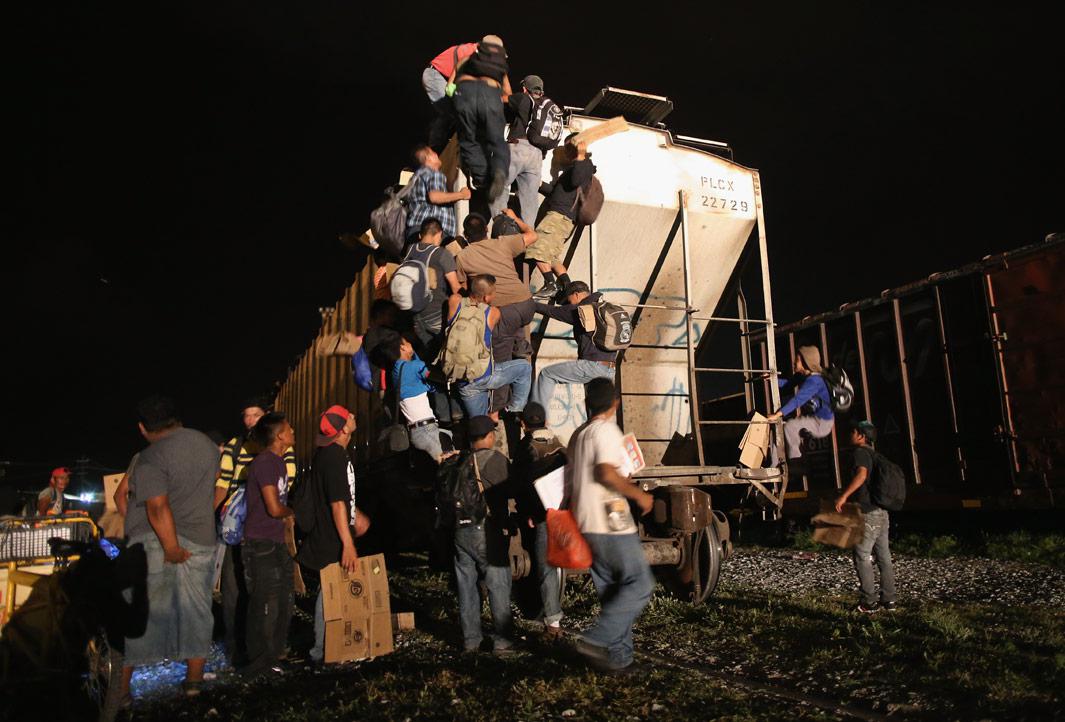 Arriaga, Mexico Central American migrants climb atop a freight train headed north early on August 4, 2013 in Arriaga, Mexico. Thousands of immigrants ride atop the trains, known as "la bestia," or the beast, during their long and perilous journey through Mexico to the U.S. border. Many of the immigrants are robbed or assaulted by gangs who control the train tops, while others fall asleep and tumble down, losing limbs or perishing under the wheels of the trains. Only a fraction of the immigrants who start the journey will arrive safely on their first attempt to illegally enter the United States.  