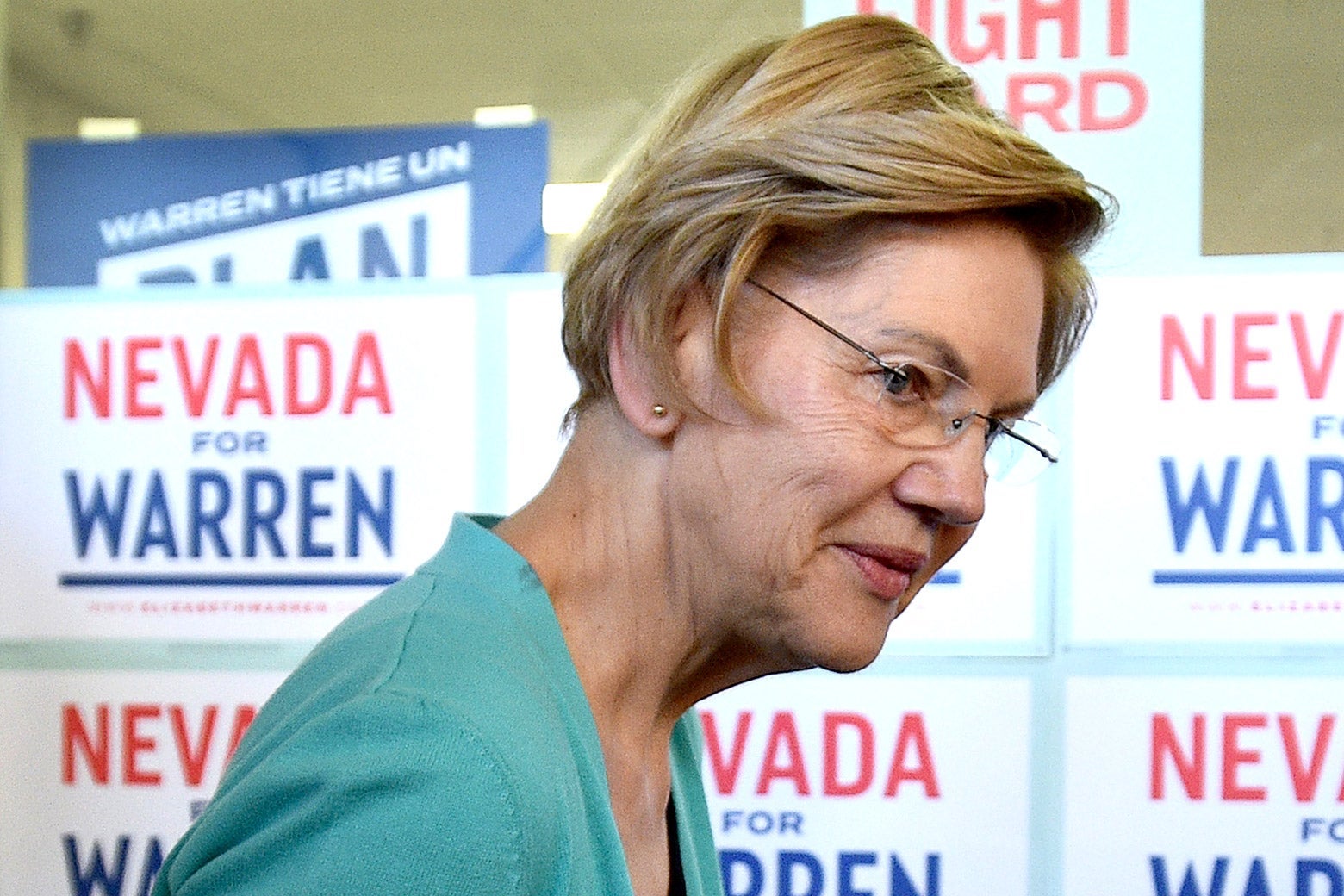 Elizabeth Warren, viewed in profile, with signs that say "Nevada for Warren" behind her.