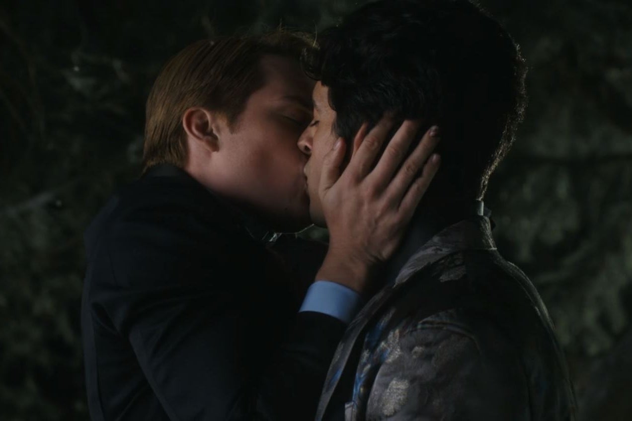 A medium close-up of Henry grabbing Alex's face as he kisses him underneath a tree at night.