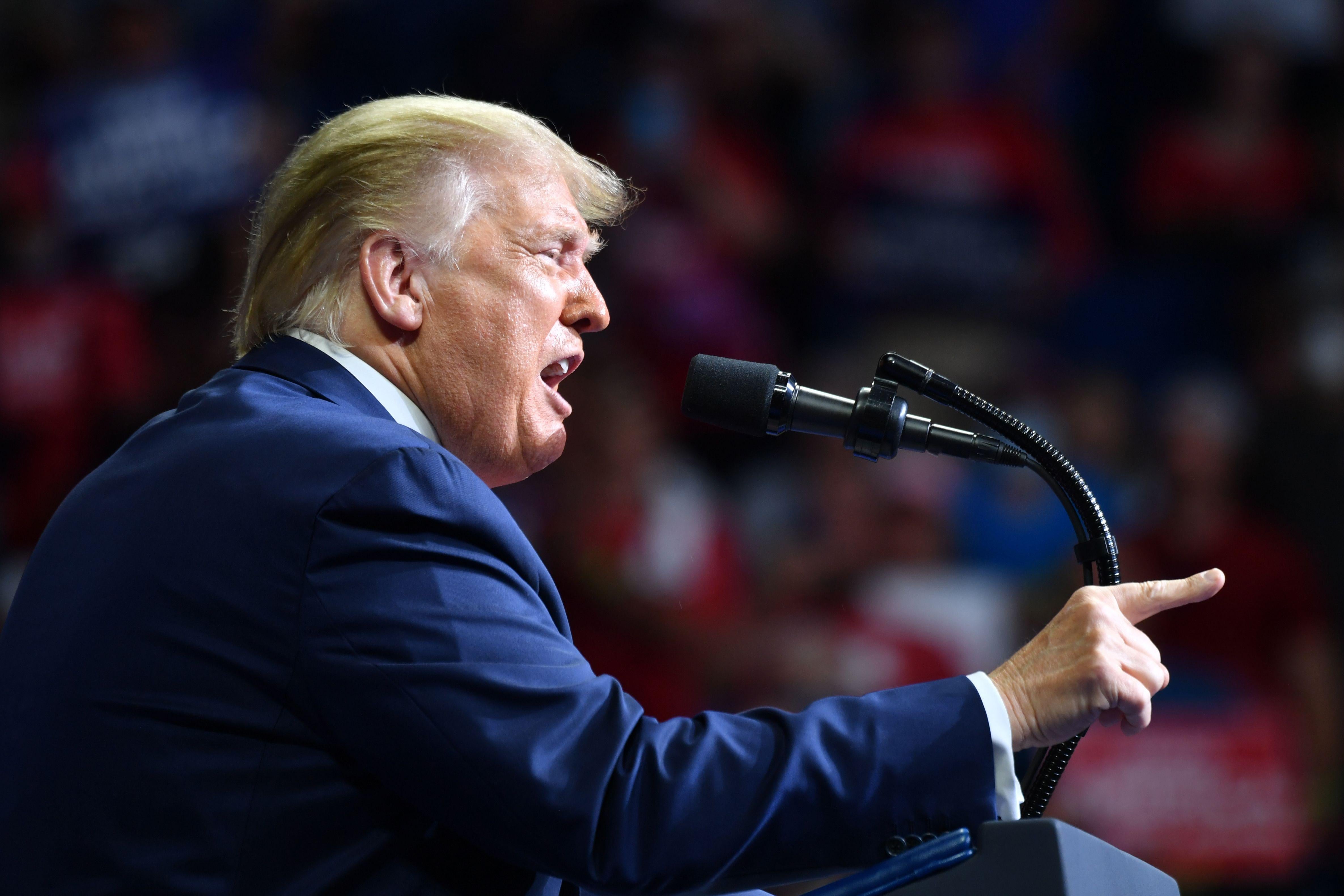 Donald Trump at a podium at his Tulsa rally, pointing his fingers and grimacing.