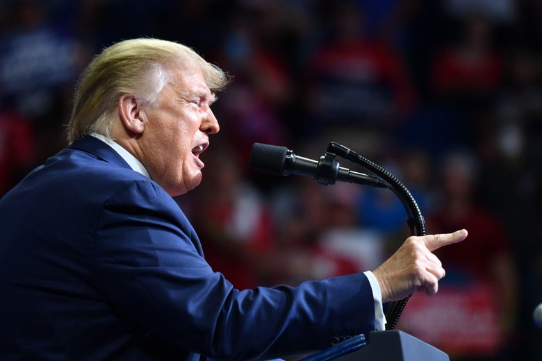 Donald Trump at a podium at his Tulsa rally, pointing his fingers and grimacing.