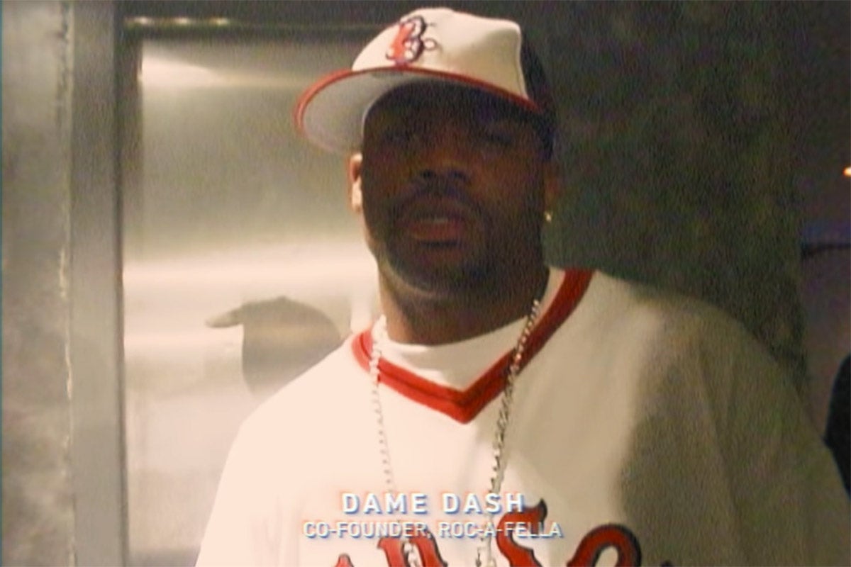 Dame Dash in a Red Sox fitted hat and an oversize vintage Red Sox baseball jersey.