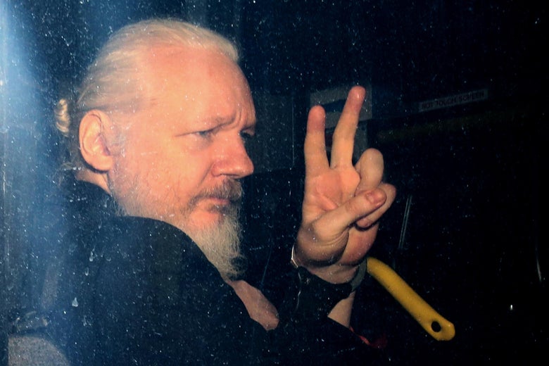 Julian Assange gestures to the media from a police vehicle upon his arrival at Westminster Magistrates’ Court.