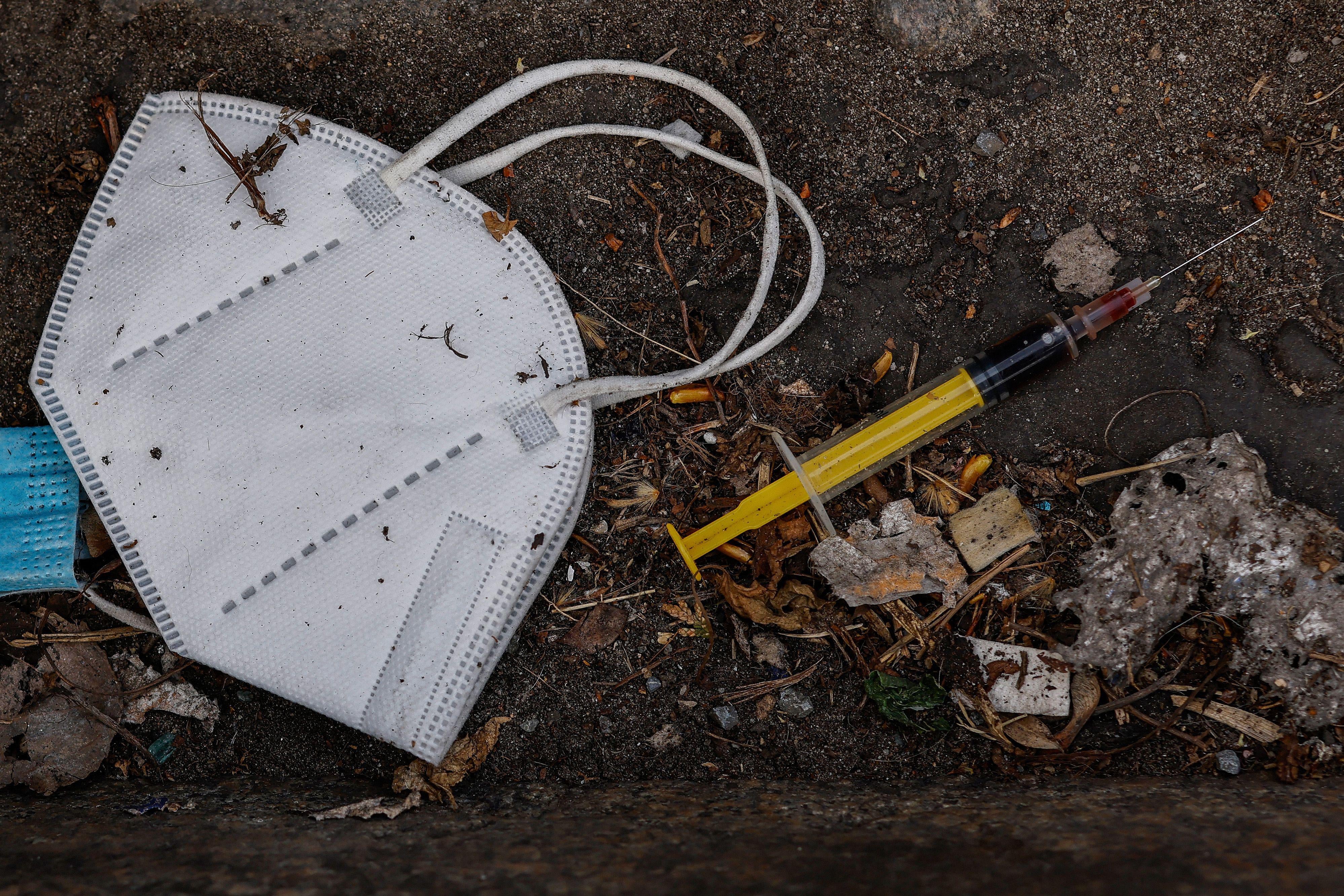 A mask and a syringe are seen on the ground.