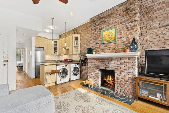 A living room with a fireplace and a washer dryer in the kitchen
