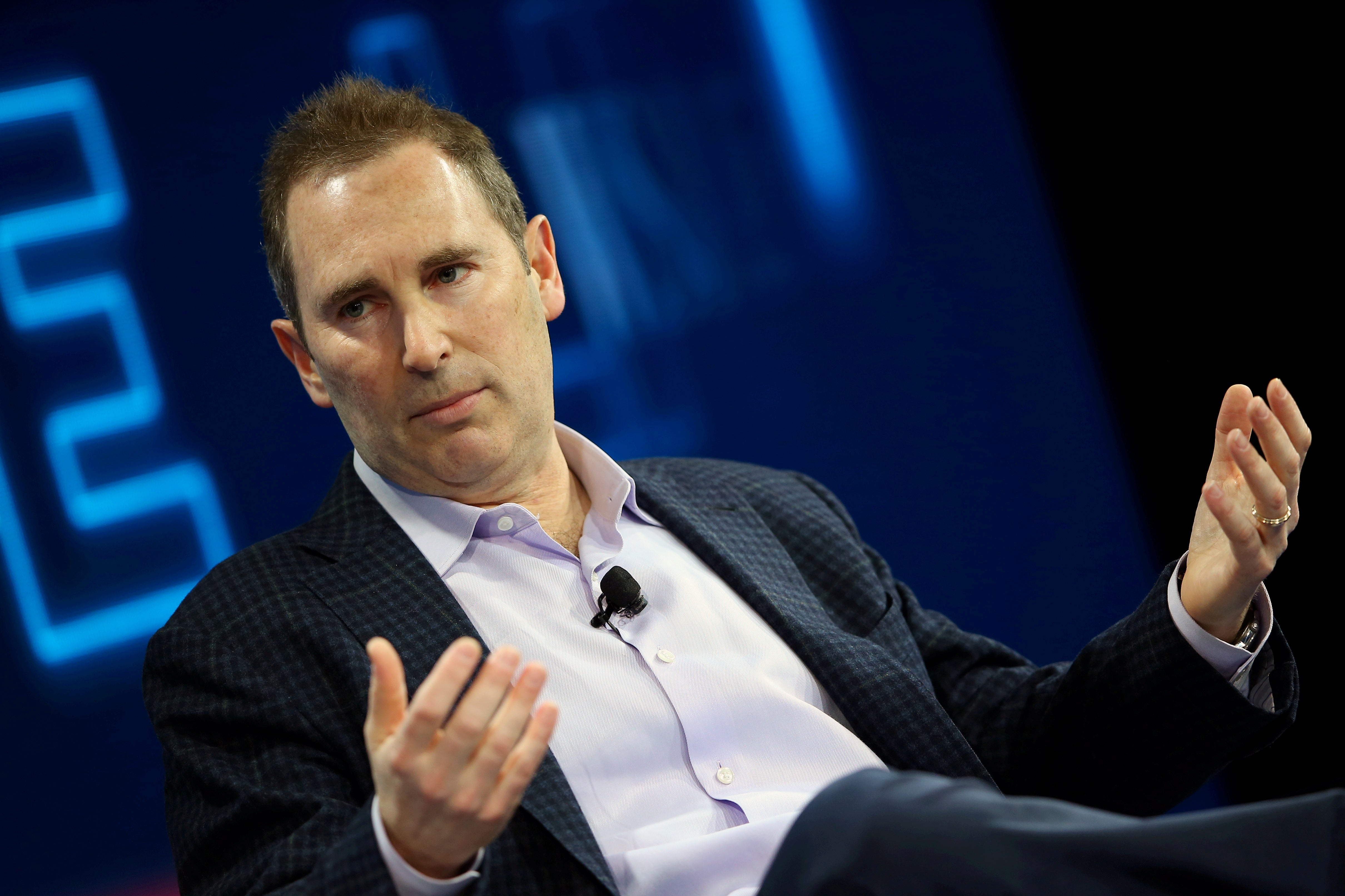 Andy Jassy, seated, gestures as he speaks onstage at a conference.
