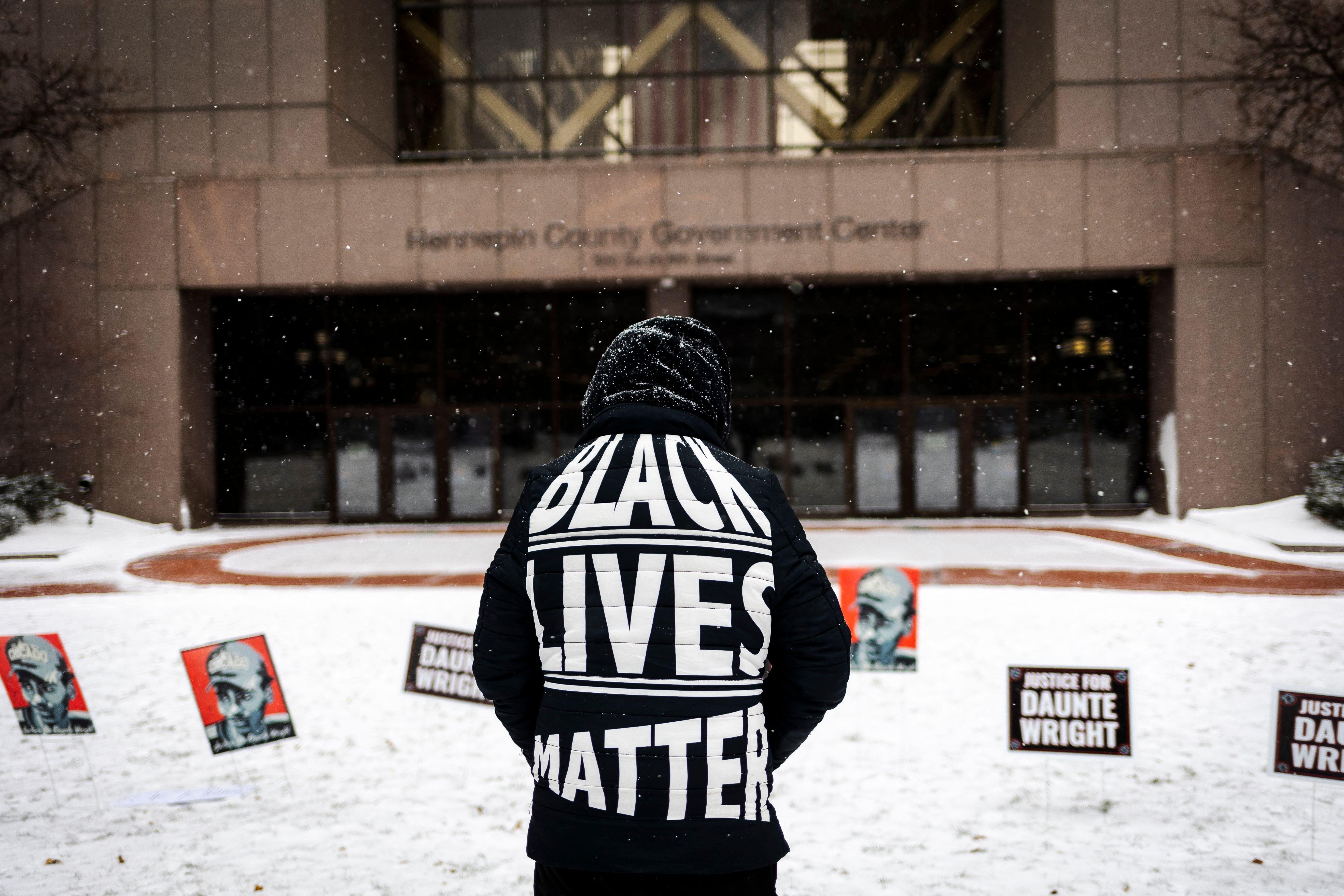A man stands in front of a government building wearing a shirt that reads, "Black lives matter."