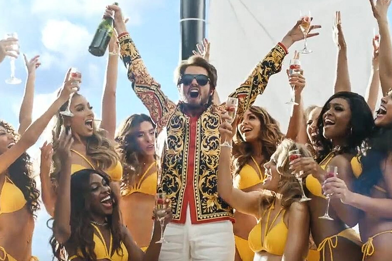 An unrecognizable Taylor Swift in a beard and sunglasses, triumphant, amid a field of women in bikinis