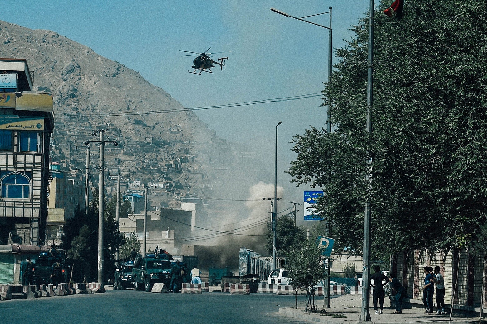Smoke rises above a street with a helicopter overhead.