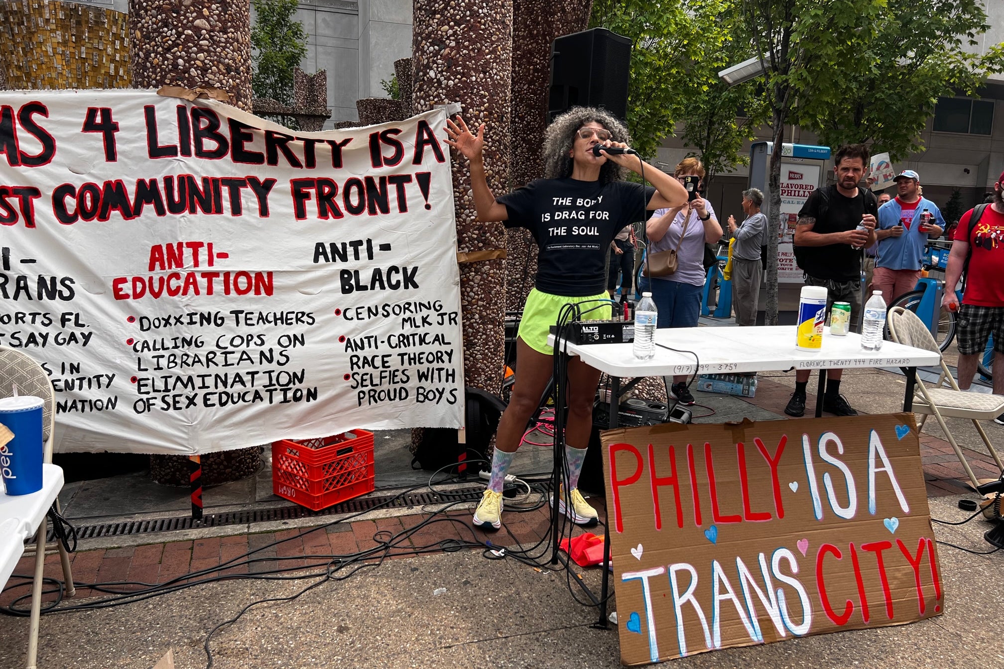 A protestor in front of a table with a sign reading "Philly Is a Trans City." 