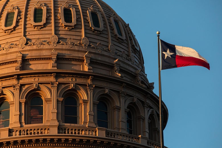 The Texas flag flies next to the state Capitol.