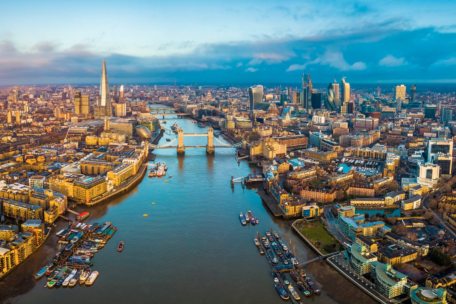 A panoramic aerial skyline view of London that includes the Thames River

