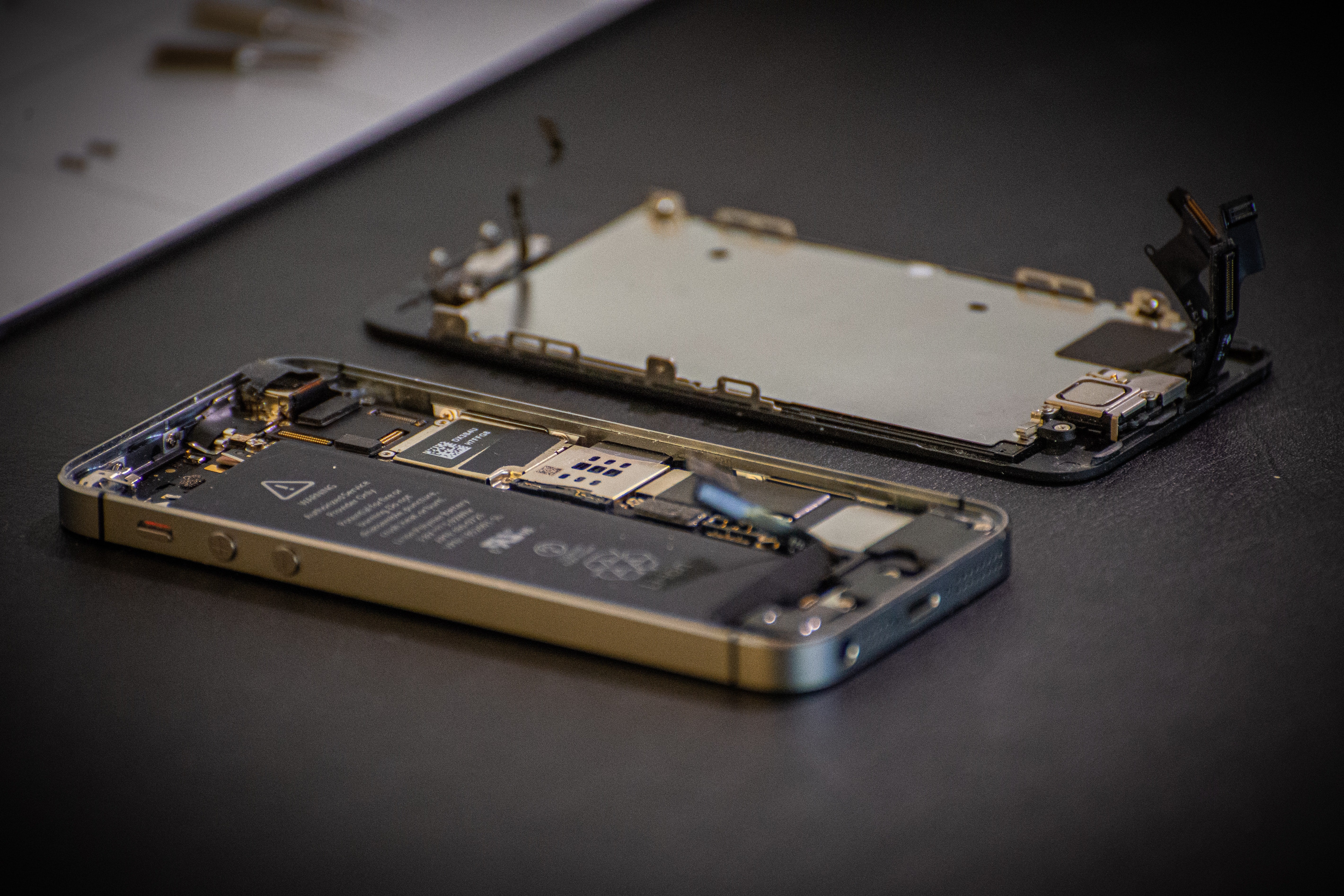 An opened iPhone lies on a table in two halves.
