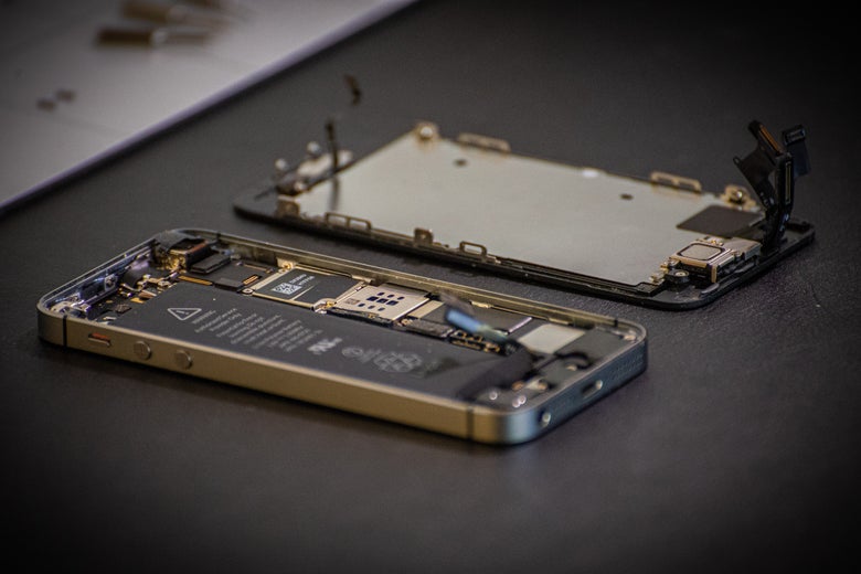 An opened iPhone lies on a table in two halves.