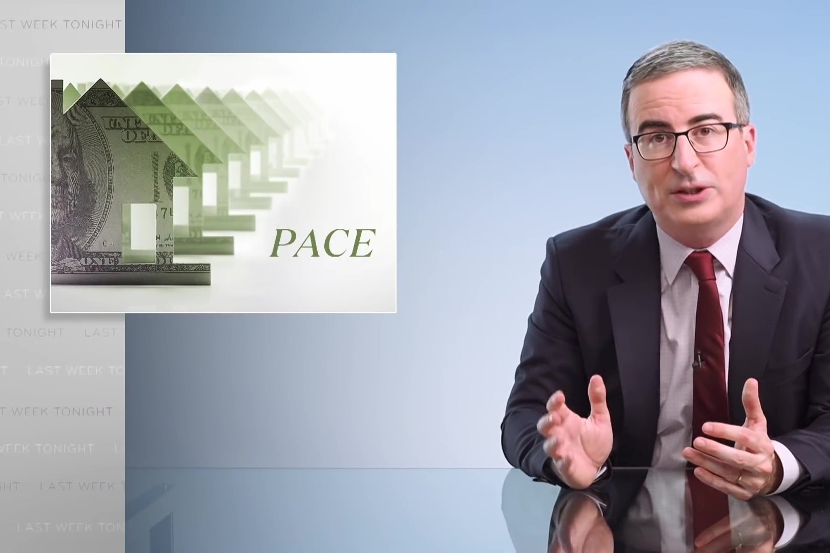 John Oliver sits at a glass anchorperson desk, in front of a graphic reading "PACE." 