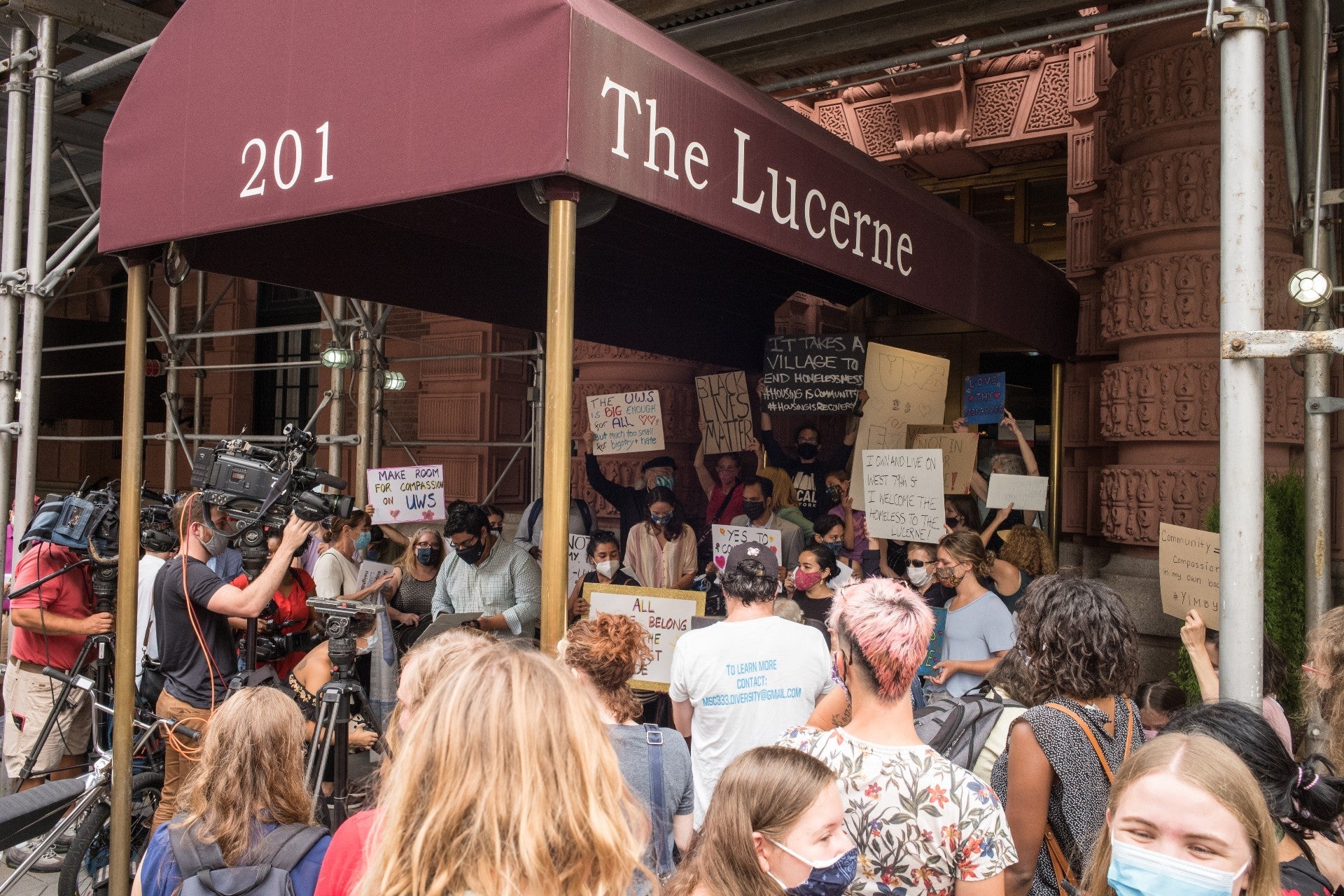 Protesters stand beneath and around an awning that says Lucerne.
