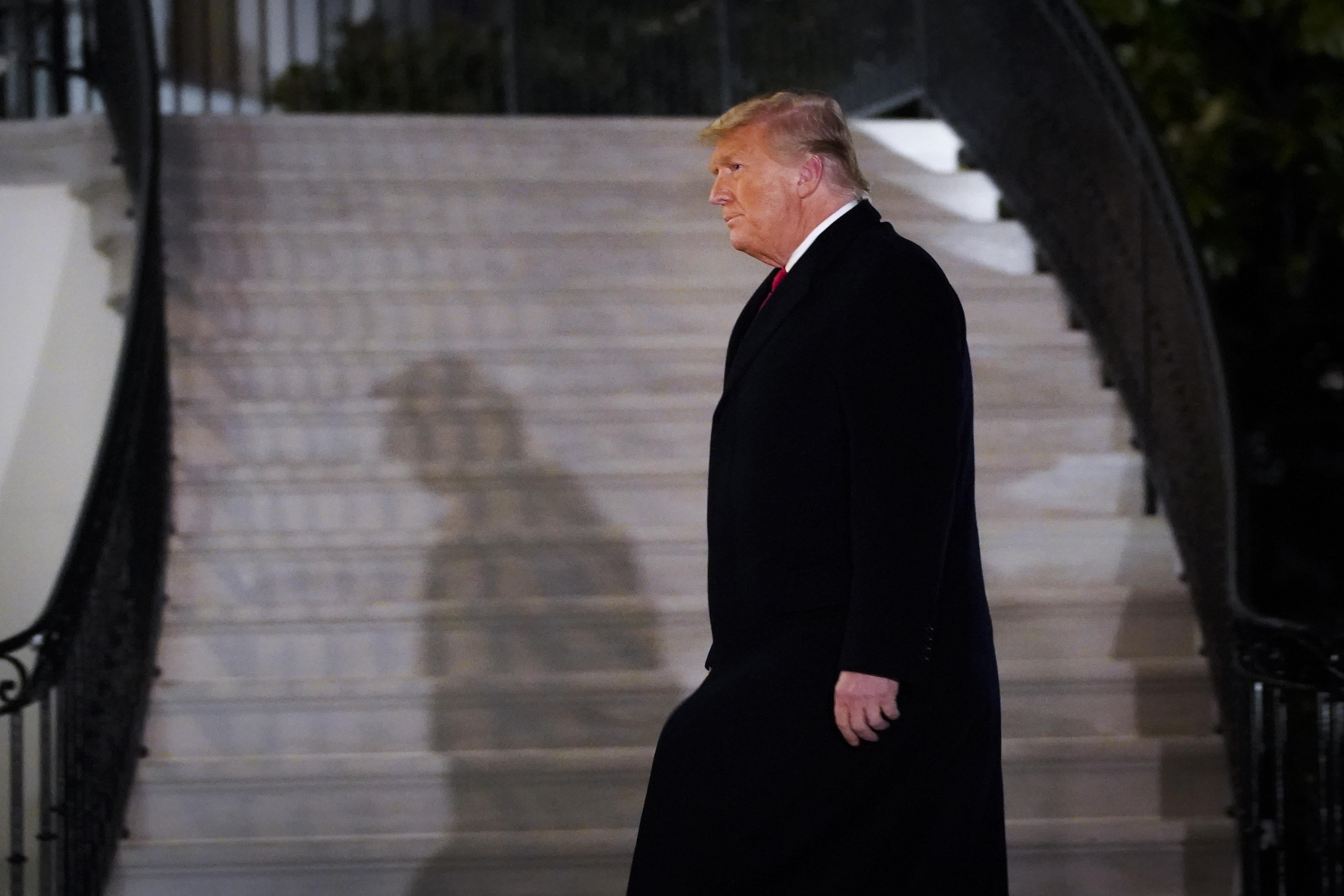 Donald Trump walks past a staircase outside at night