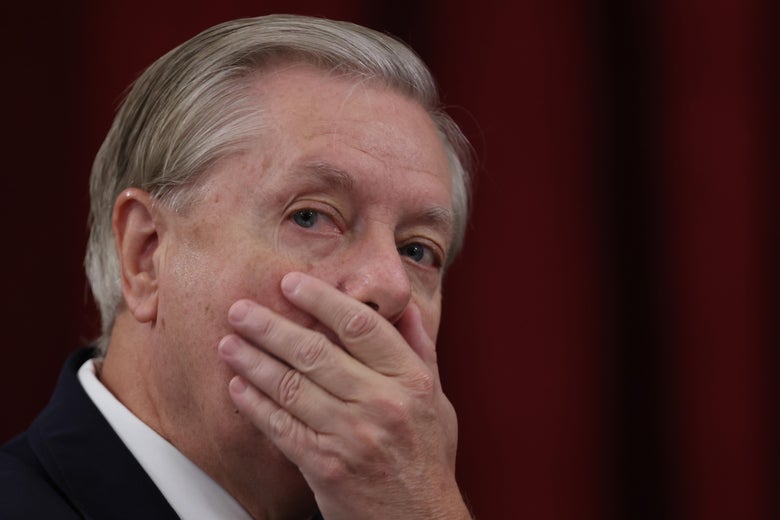 Lindsey Graham covers his mouth with his hand.